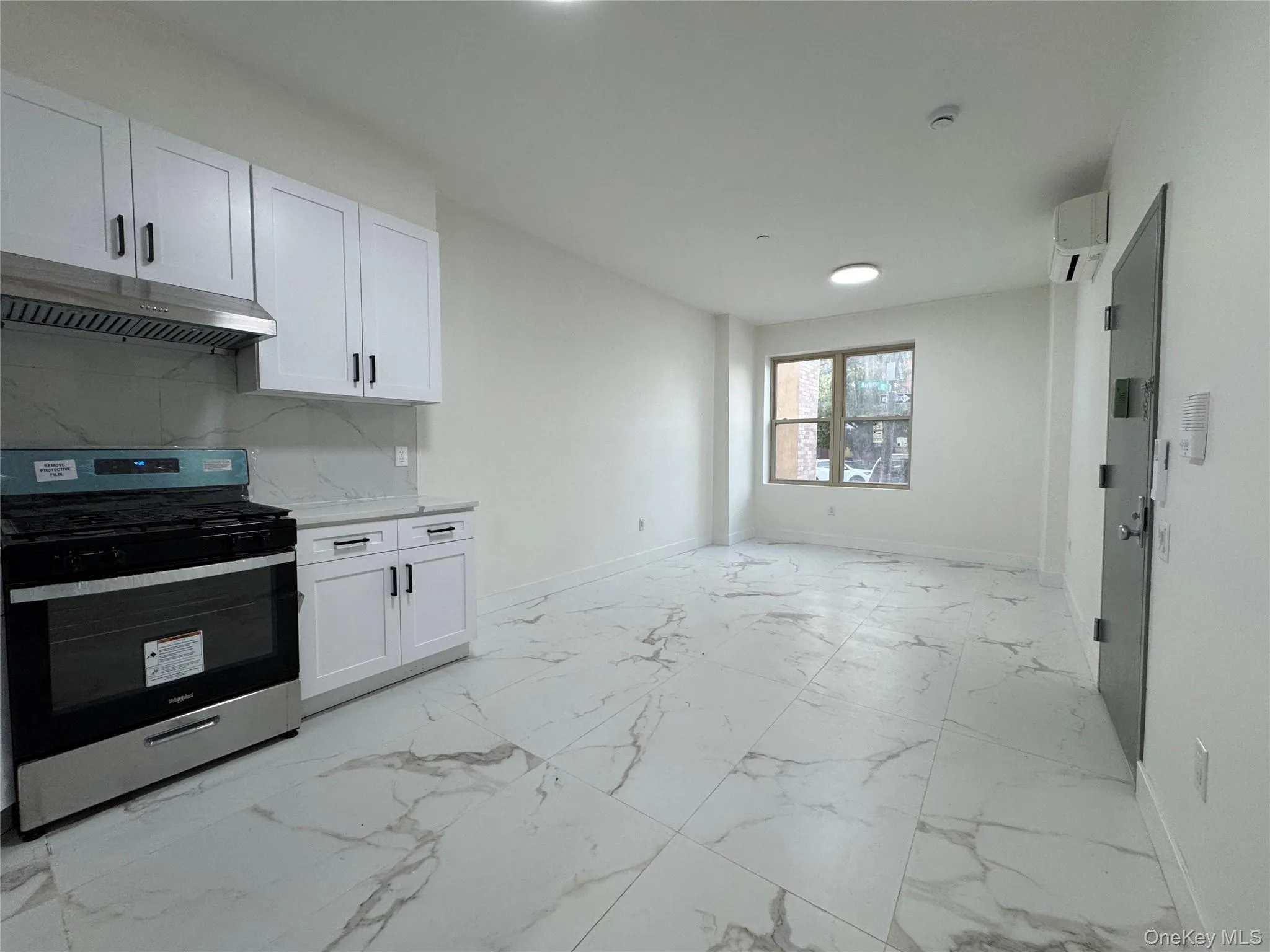 Kitchen with stainless steel range oven, white cabinets, under cabinet range hood, light marble finish floors, and backsplash Kitchen with stainless steel range oven, white cabinets, under cabinet range hood, light marble finish floors, and backsplash