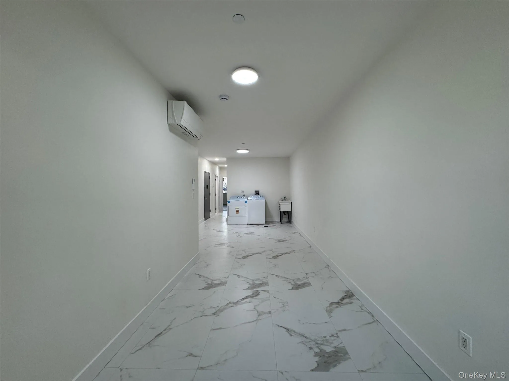 Hall with light marble finish floors and an AC wall unit Hall with light marble finish floors and an AC wall unit