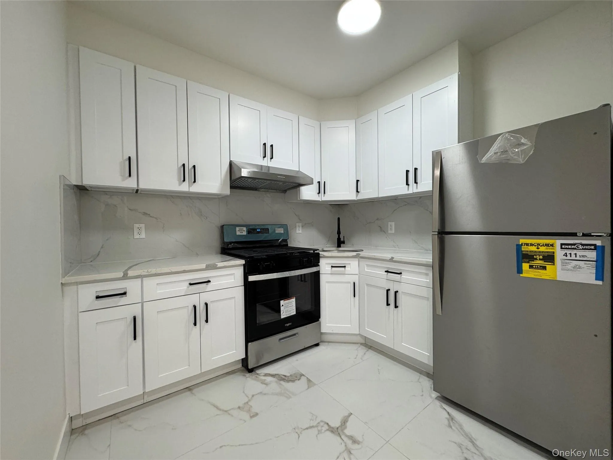Kitchen featuring appliances with stainless steel finishes, white cabinetry, and decorative backsplash Kitchen featuring appliances with stainless steel finishes, white cabinetry, and decorative backsplash