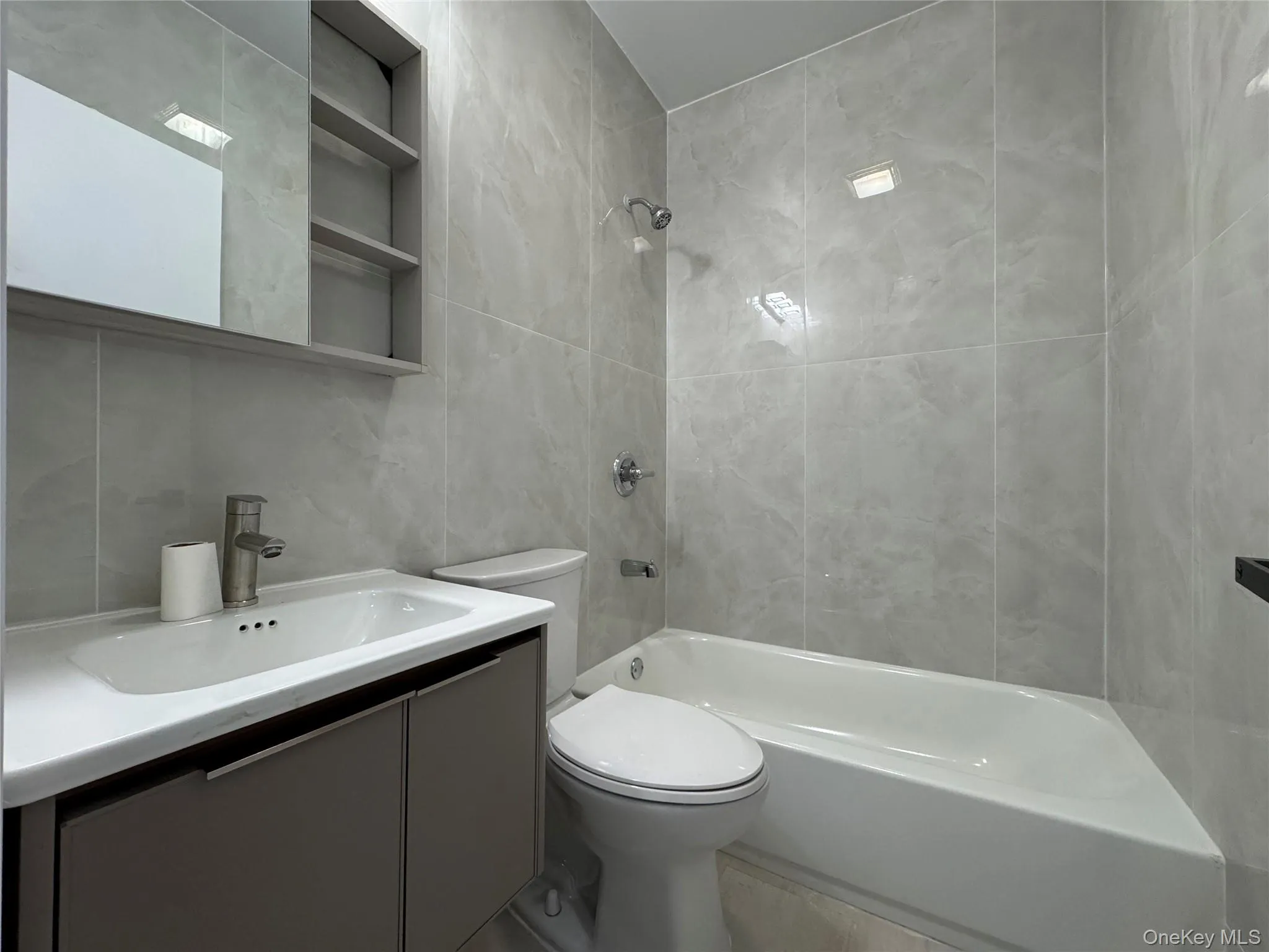 Bathroom featuring tile walls, vanity, and bathtub / shower combination Bathroom featuring tile walls, vanity, and bathtub / shower combination