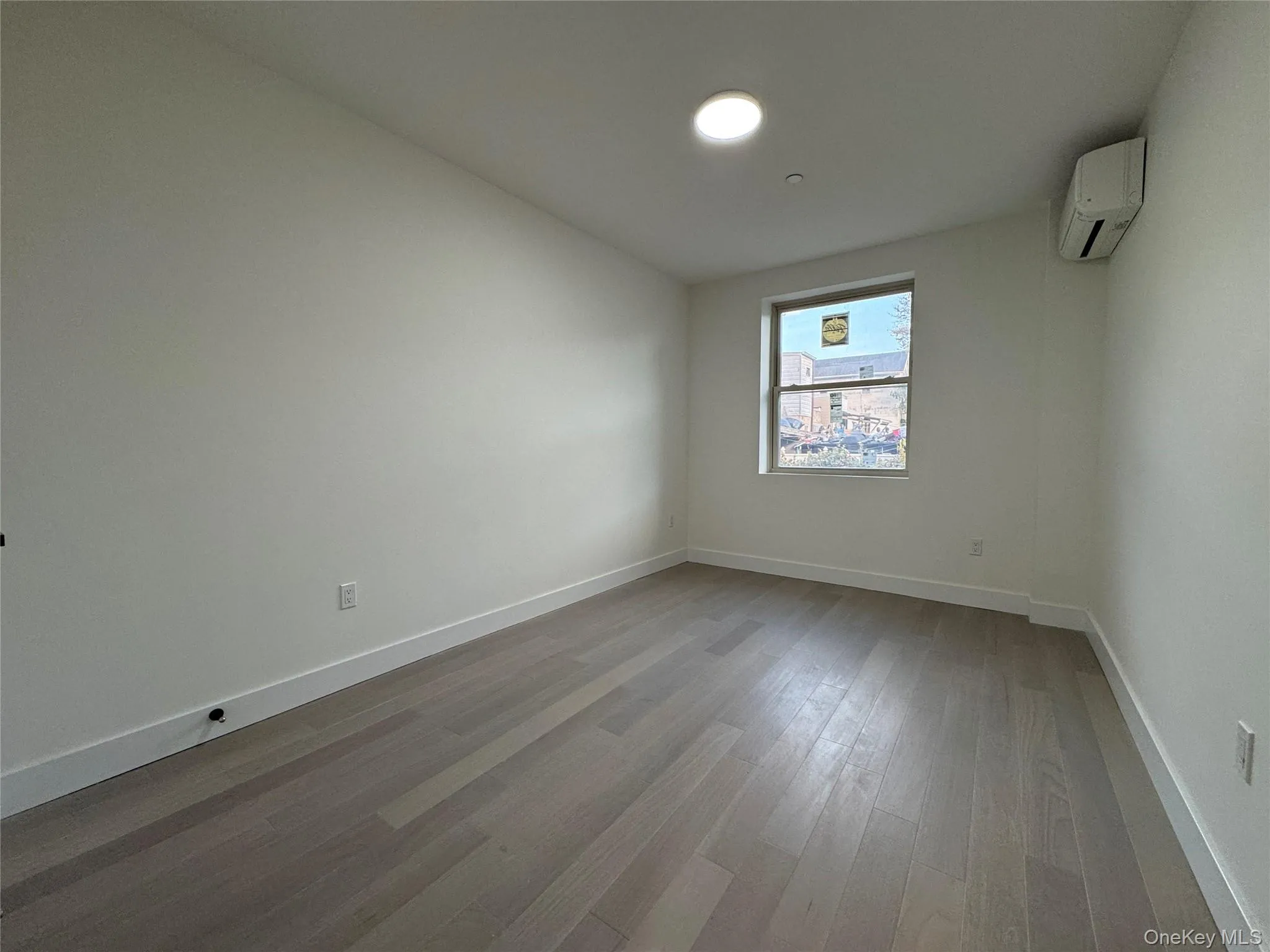Empty room with light wood-style floors and a wall mounted AC Empty room with light wood-style floors and a wall mounted AC