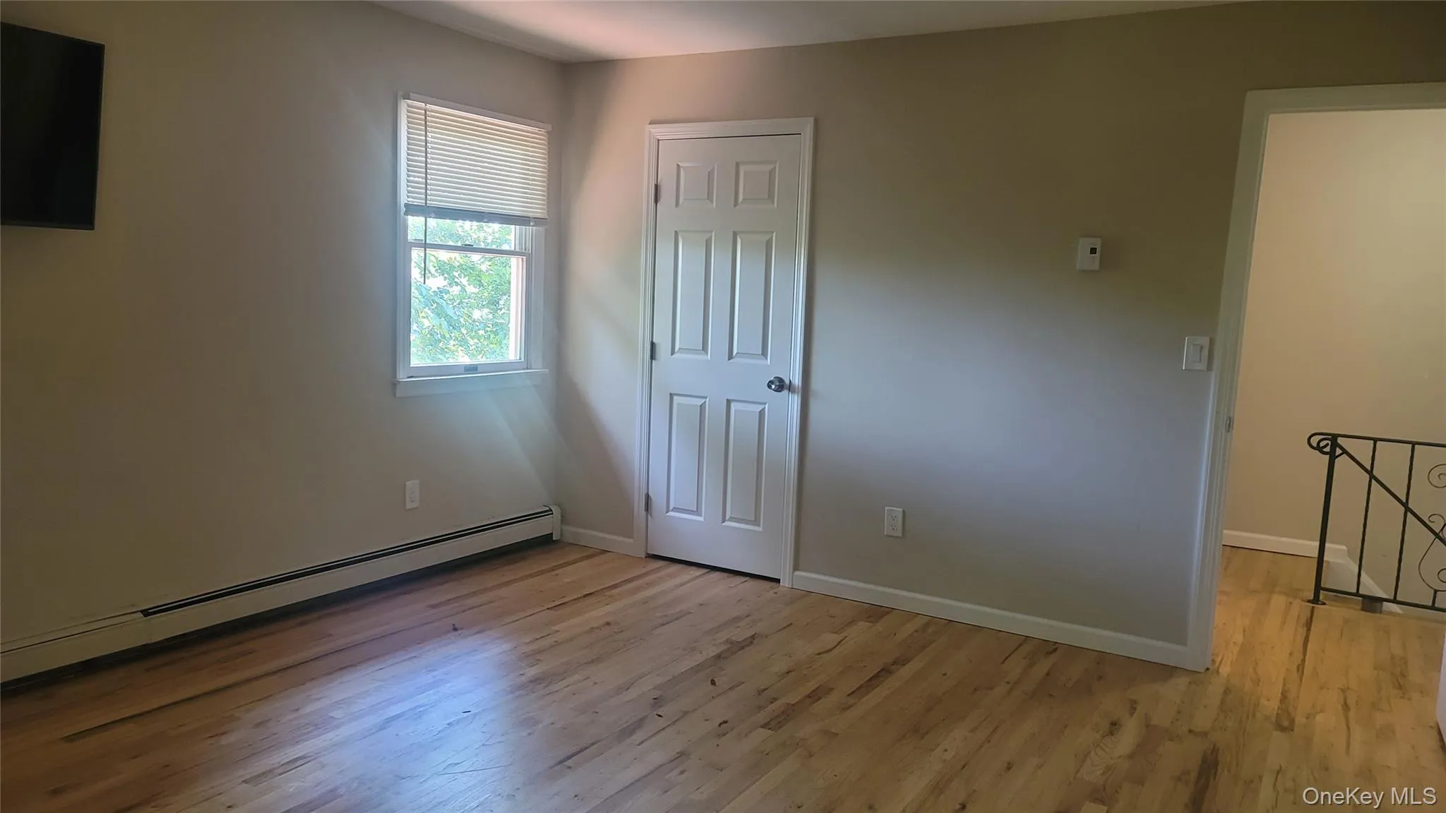 Unfurnished bedroom featuring baseboard heating and light wood-style floors Unfurnished bedroom featuring baseboard heating and light wood-style floors