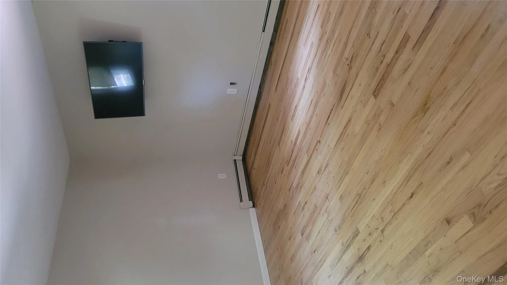 Unfurnished room featuring light wood-style flooring and baseboard heating Unfurnished room featuring light wood-style flooring and baseboard heating