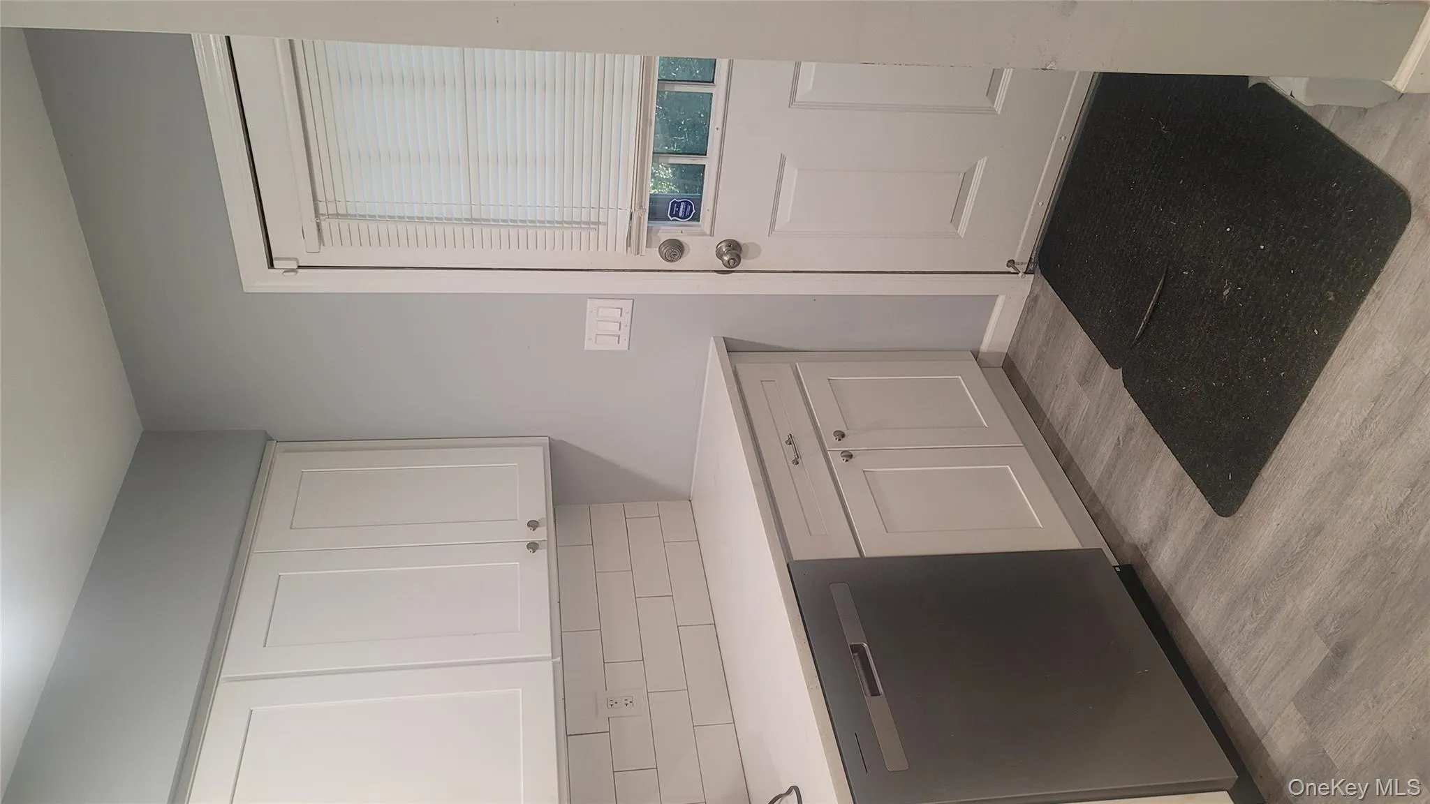 Kitchen with white cabinetry, dishwashing machine, light wood-type flooring, and tasteful backsplash Kitchen with white cabinetry, dishwashing machine, light wood-type flooring, and tasteful backsplash