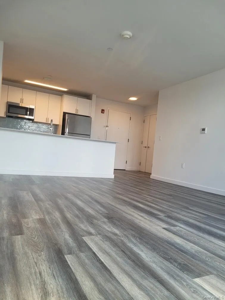 Unfurnished living room with dark wood-type flooring and baseboards Unfurnished living room with dark wood-type flooring and baseboards