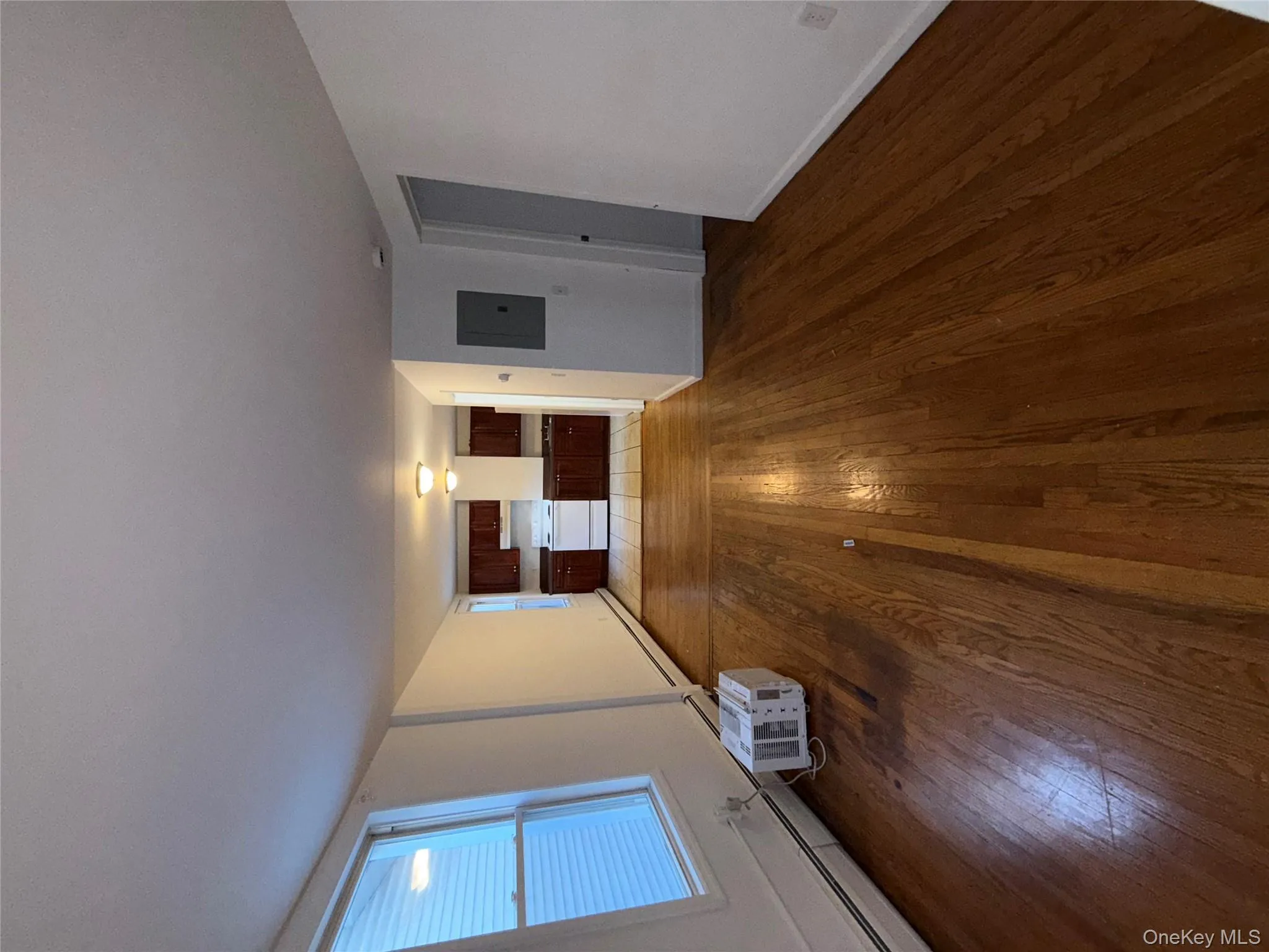 Unfurnished living room with dark wood-style flooring, electric panel, and baseboard heating Unfurnished living room with dark wood-style flooring, electric panel, and baseboard heating