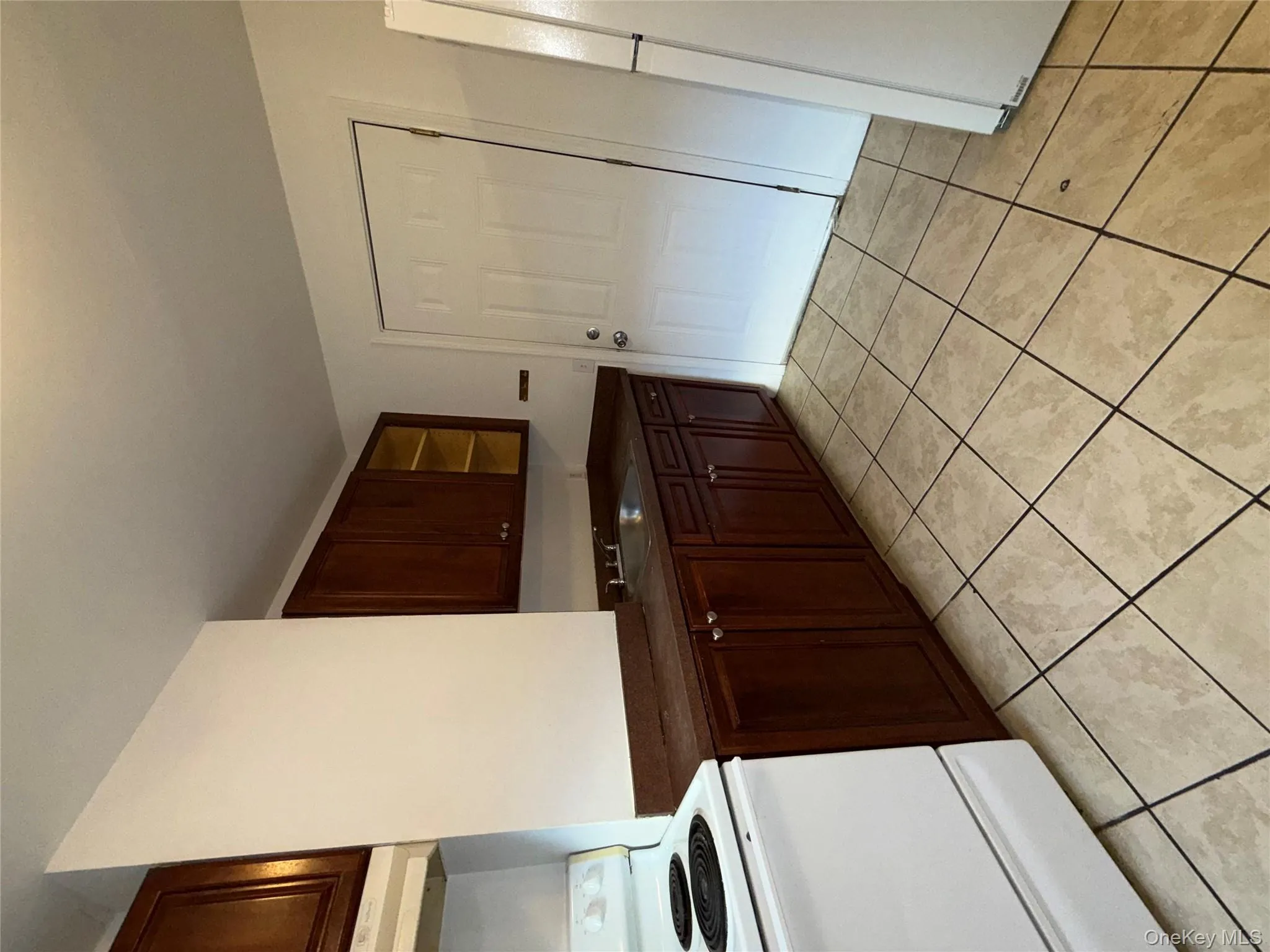 Kitchen with dark countertops, stove, light tile patterned floors, fridge, and extractor fan Kitchen with dark countertops, stove, light tile patterned floors, fridge, and extractor fan