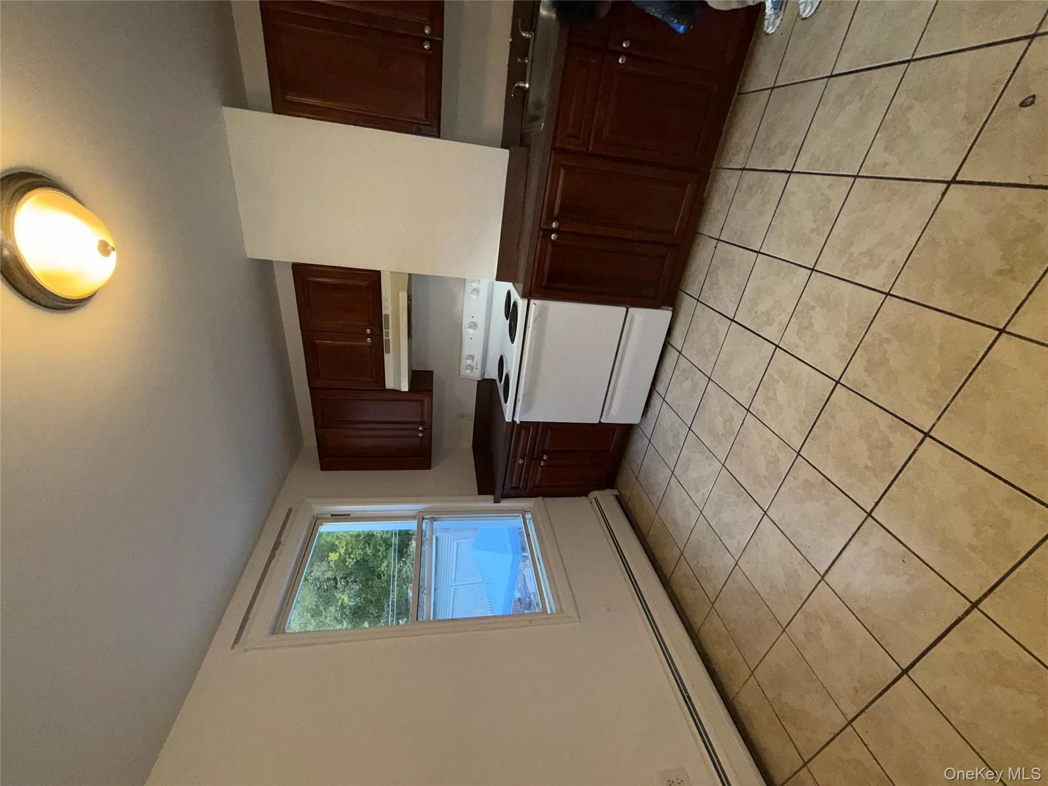 Kitchen with dark countertops, a baseboard radiator, light tile patterned floors, and electric range Kitchen with dark countertops, a baseboard radiator, light tile patterned floors, and electric range