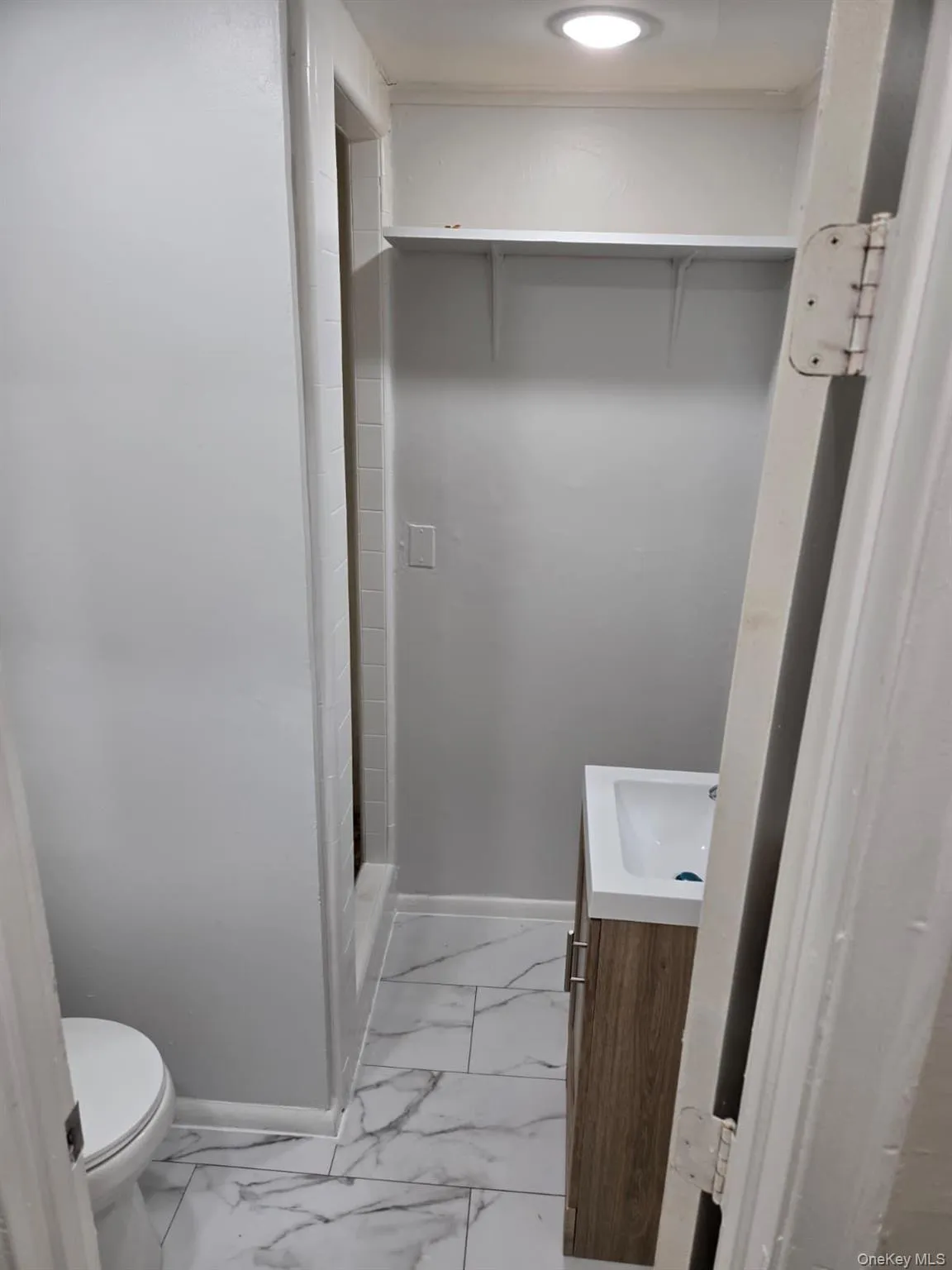Bathroom featuring vanity, a shower stall, and light marble finish floors Bathroom featuring vanity, a shower stall, and light marble finish floors