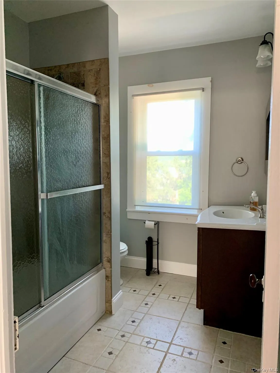 Bathroom featuring vanity, light tile patterned flooring, and shower / bath combination with glass door Bathroom featuring vanity, light tile patterned flooring, and shower / bath combination with glass door