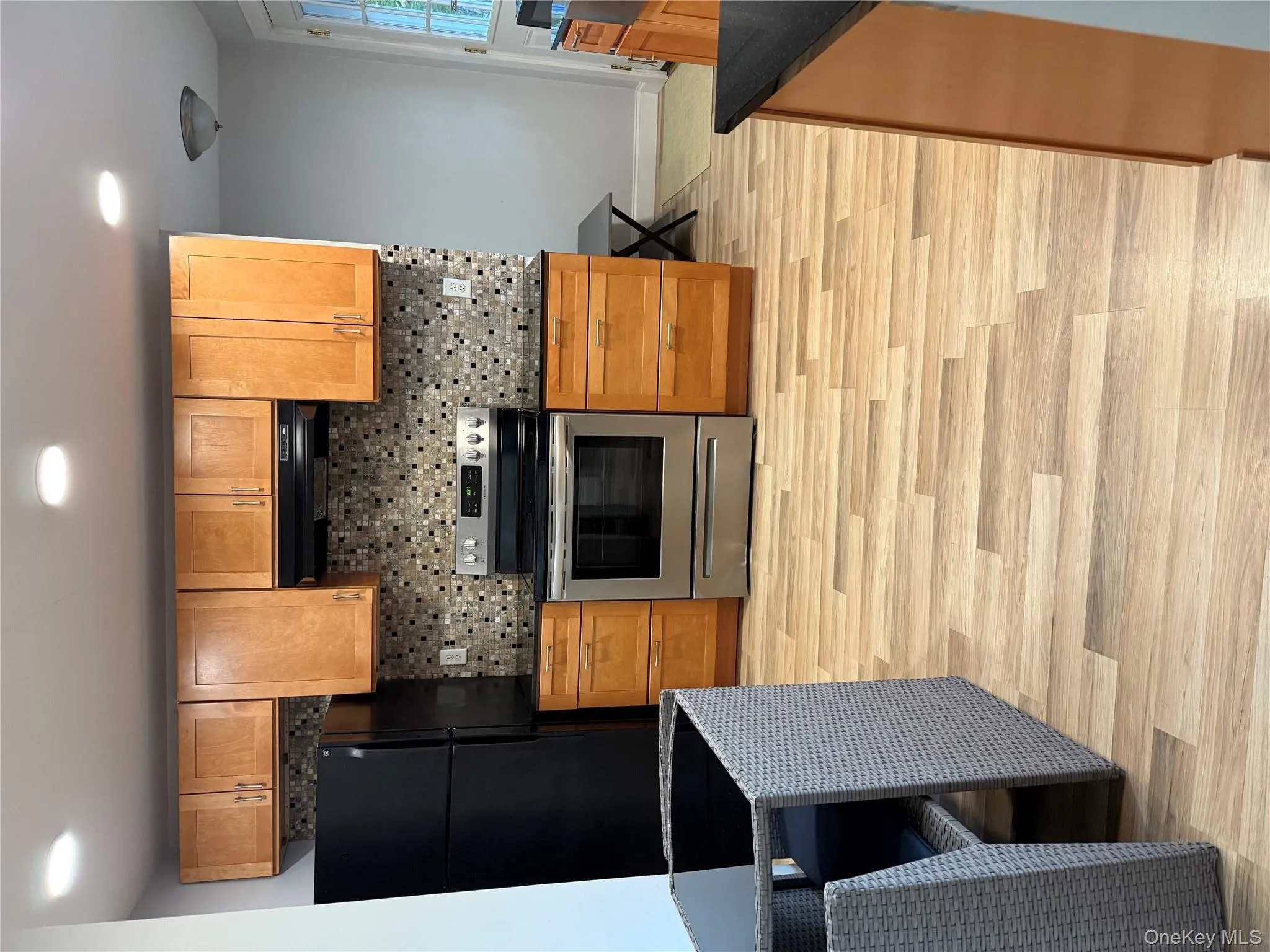 Kitchen featuring electric stove, tasteful backsplash, black fridge, light wood-type flooring, and ventilation hood Kitchen featuring electric stove, tasteful backsplash, black fridge, light wood-type flooring, and ventilation hood