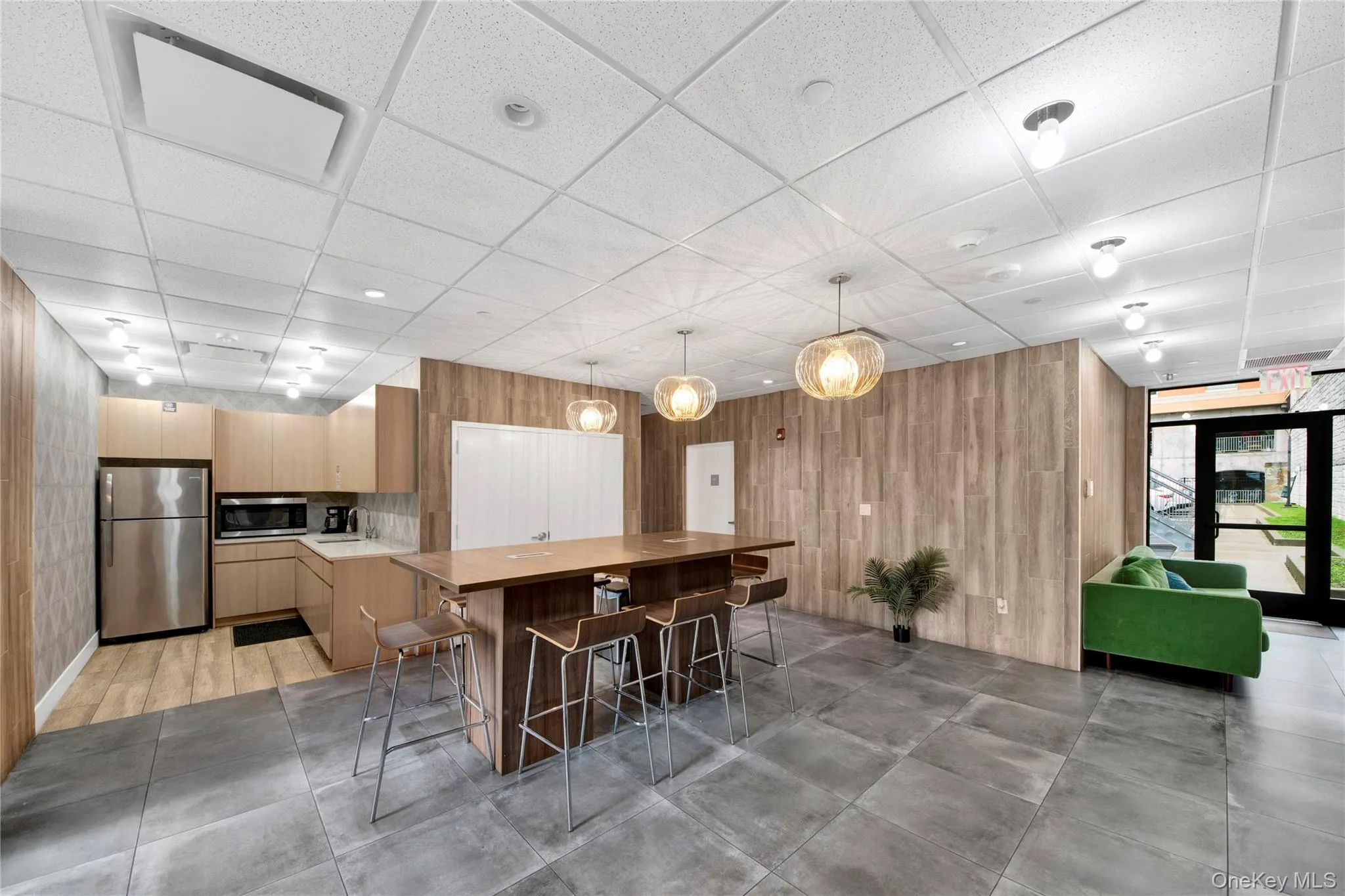 Kitchen featuring decorative light fixtures, a breakfast bar, stainless steel appliances, wood walls, and a center island Kitchen featuring decorative light fixtures, a breakfast bar, stainless steel appliances, wood walls, and a center island