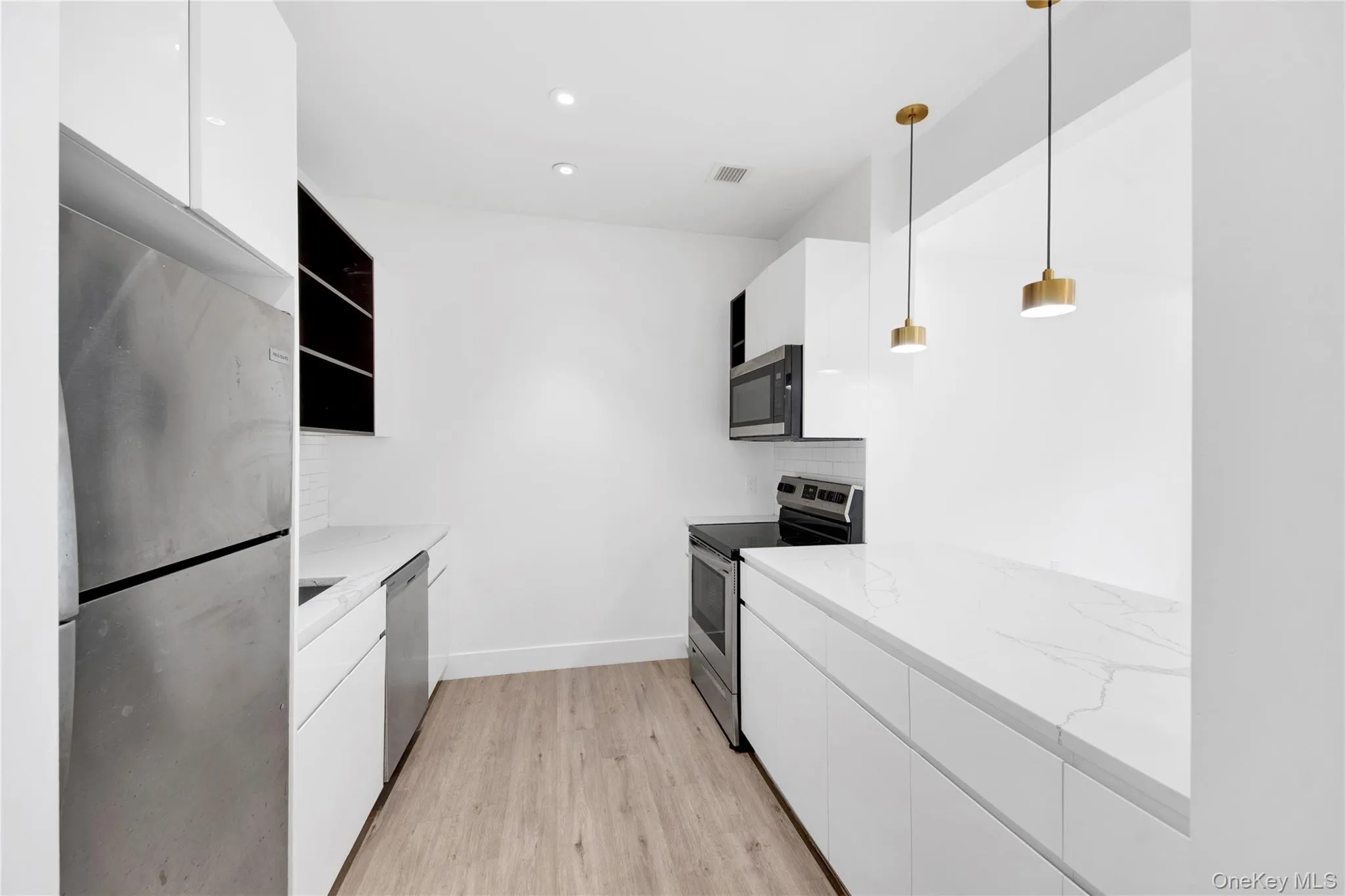 Kitchen with white cabinetry, modern cabinets, stainless steel appliances, light wood finished floors, and recessed lighting Kitchen with white cabinetry, modern cabinets, stainless steel appliances, light wood finished floors, and recessed lighting