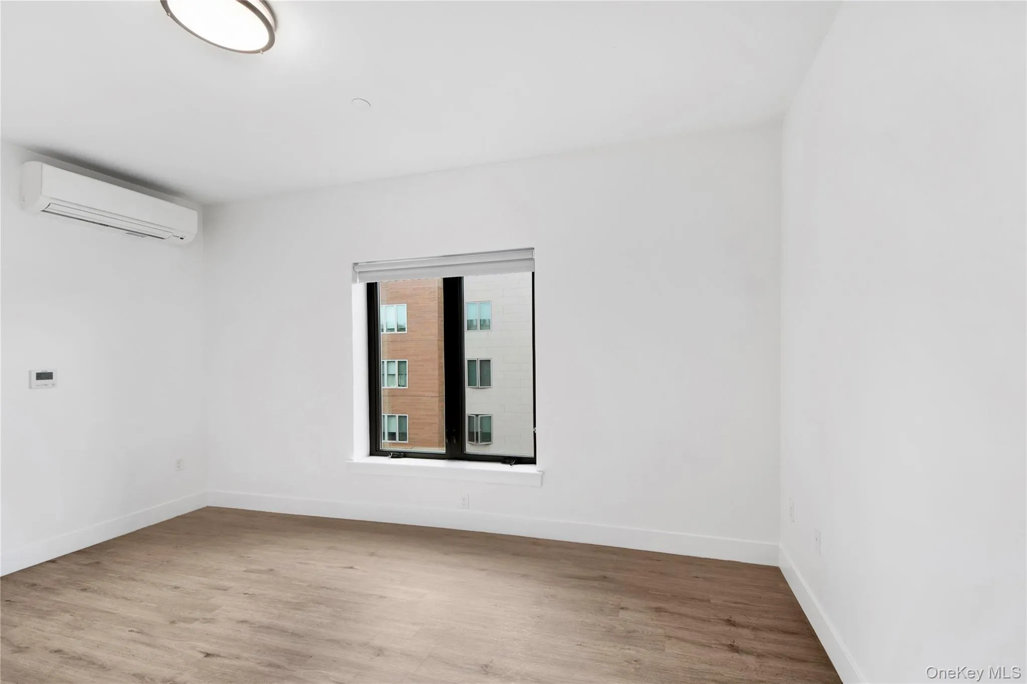 Empty room featuring light wood-style floors and a wall mounted AC Empty room featuring light wood-style floors and a wall mounted AC