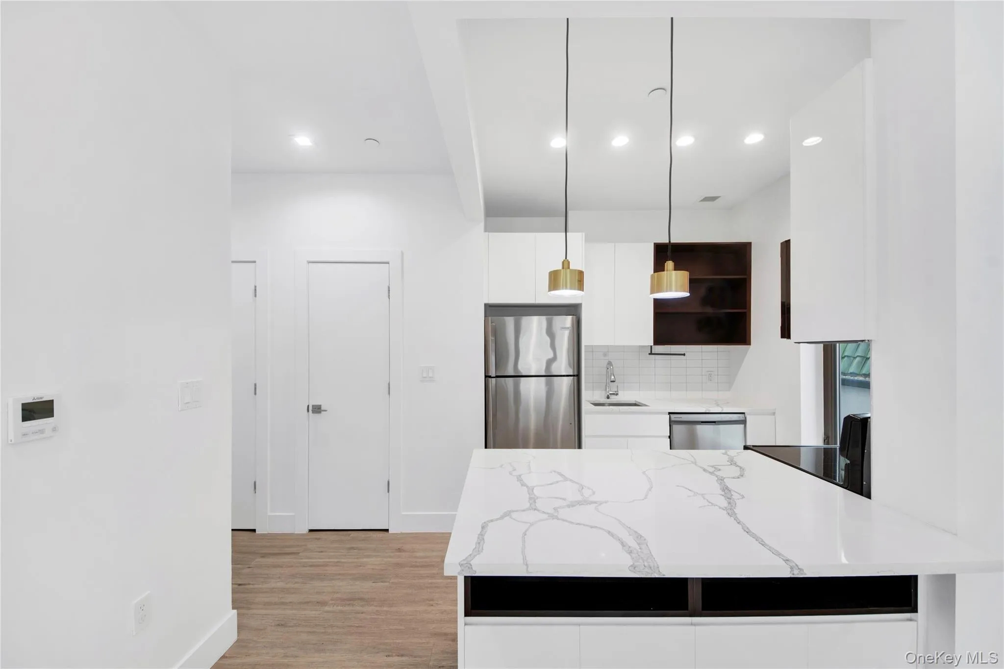 Kitchen with white cabinets, open shelves, decorative light fixtures, light stone countertops, and appliances with stainless steel finishes Kitchen with white cabinets, open shelves, decorative light fixtures, light stone countertops, and appliances with stainless steel finishes