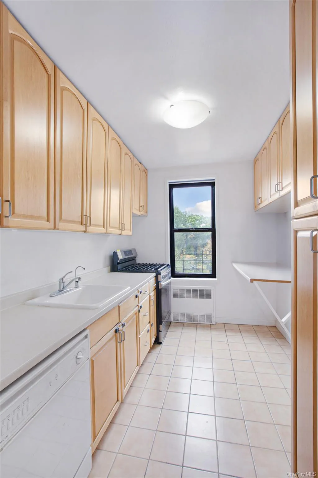 Kitchen featuring light brown cabinets, dishwasher, gas stove, and light countertops Kitchen featuring light brown cabinets, dishwasher, gas stove, and light countertops