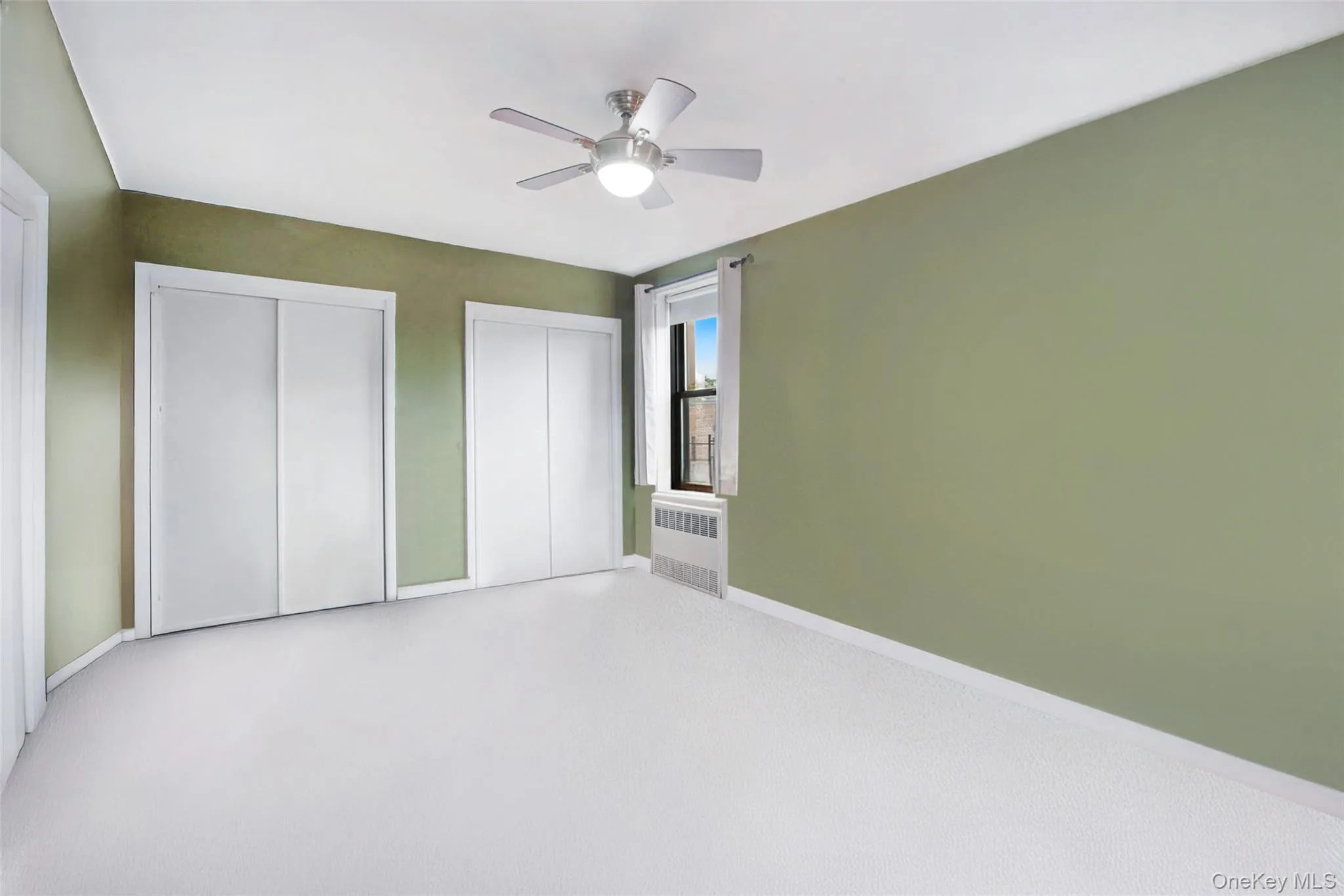 Unfurnished bedroom featuring two closets, radiator heating unit, and a ceiling fan Unfurnished bedroom featuring two closets, radiator heating unit, and a ceiling fan