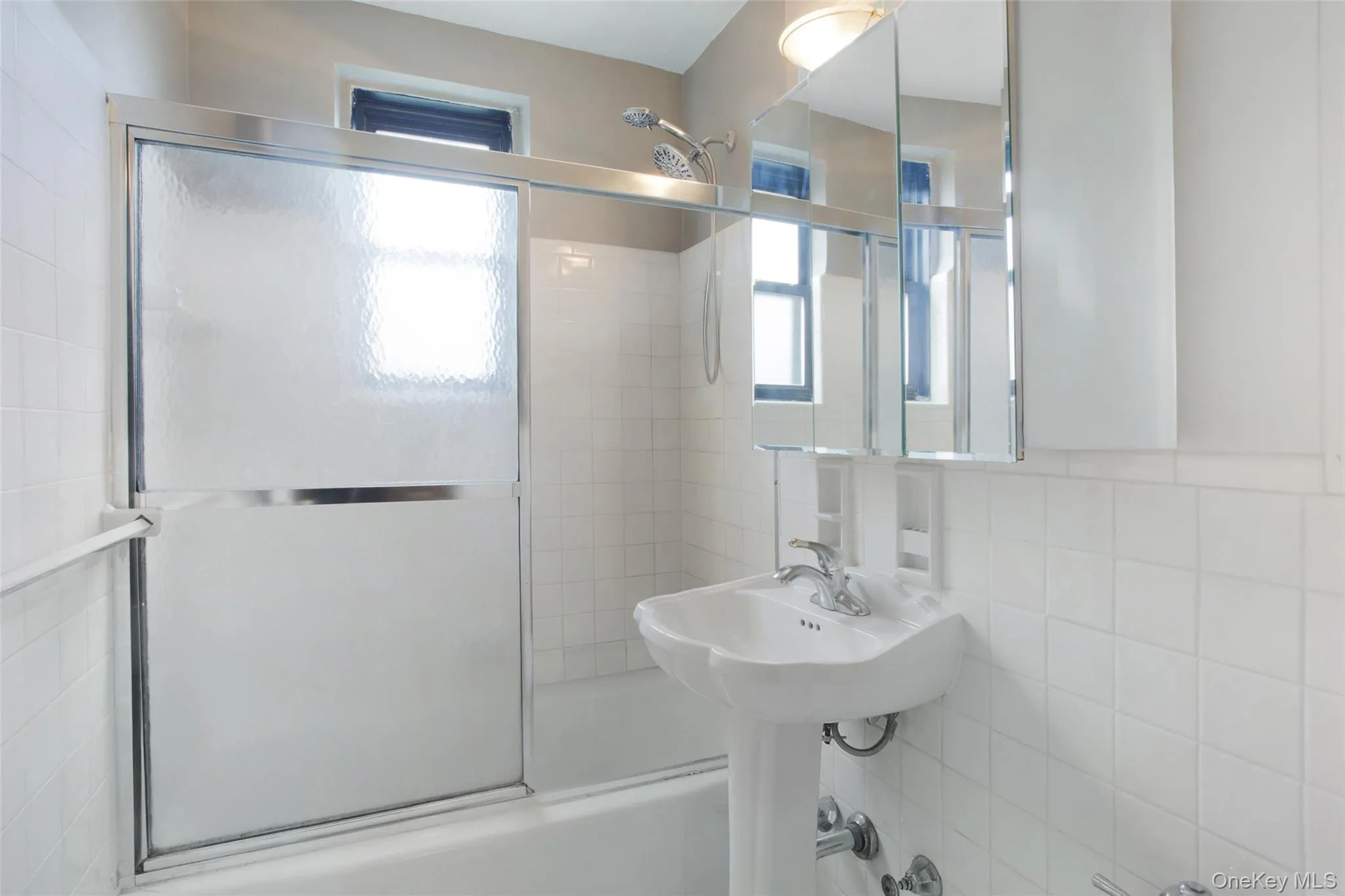 Full bathroom featuring tile walls, enclosed tub / shower combo, and decorative backsplash Full bathroom featuring tile walls, enclosed tub / shower combo, and decorative backsplash