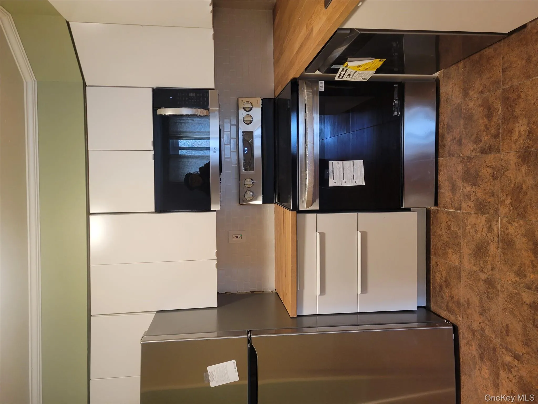 Kitchen featuring stainless steel appliances, backsplash, white cabinetry, crown molding, and butcher block counters Kitchen featuring stainless steel appliances, backsplash, white cabinetry, crown molding, and butcher block counters