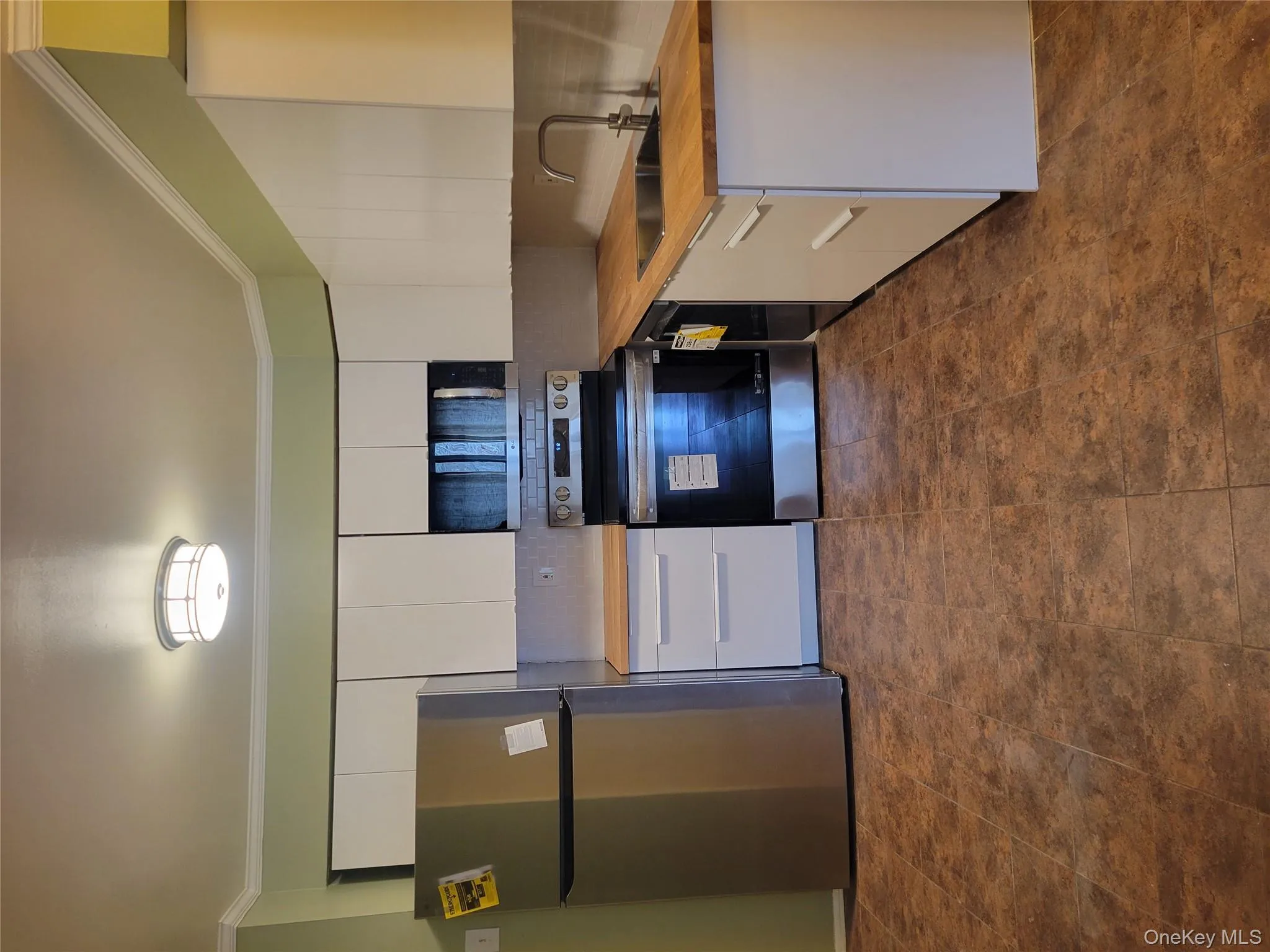 Kitchen with stainless steel appliances, ornamental molding, white cabinetry, tasteful backsplash, and butcher block counters Kitchen with stainless steel appliances, ornamental molding, white cabinetry, tasteful backsplash, and butcher block counters