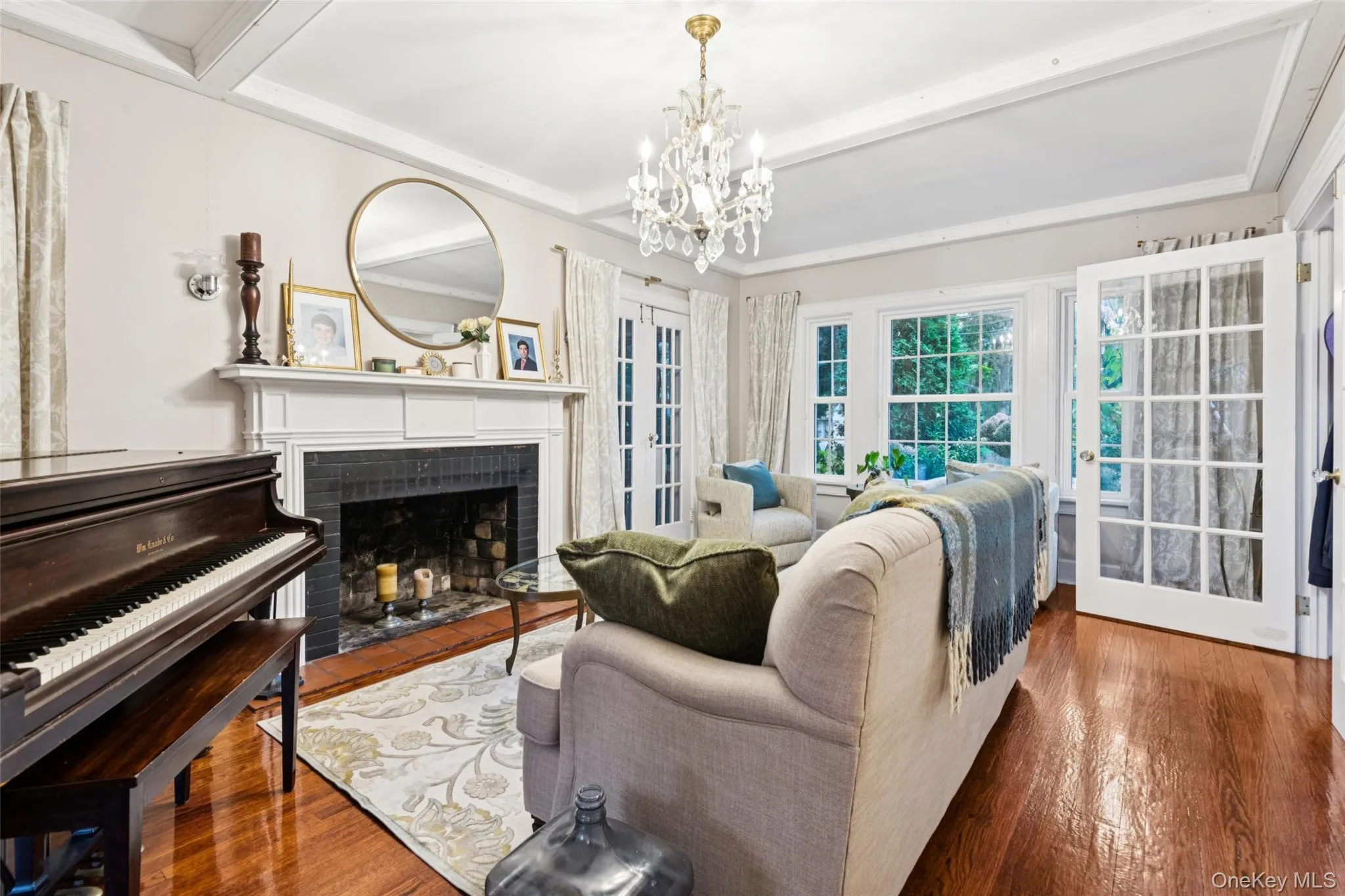 Living room with a fireplace, beamed ceiling, wood finished floors, a chandelier, and ornamental molding Living room with a fireplace, beamed ceiling, wood finished floors, a chandelier, and ornamental molding