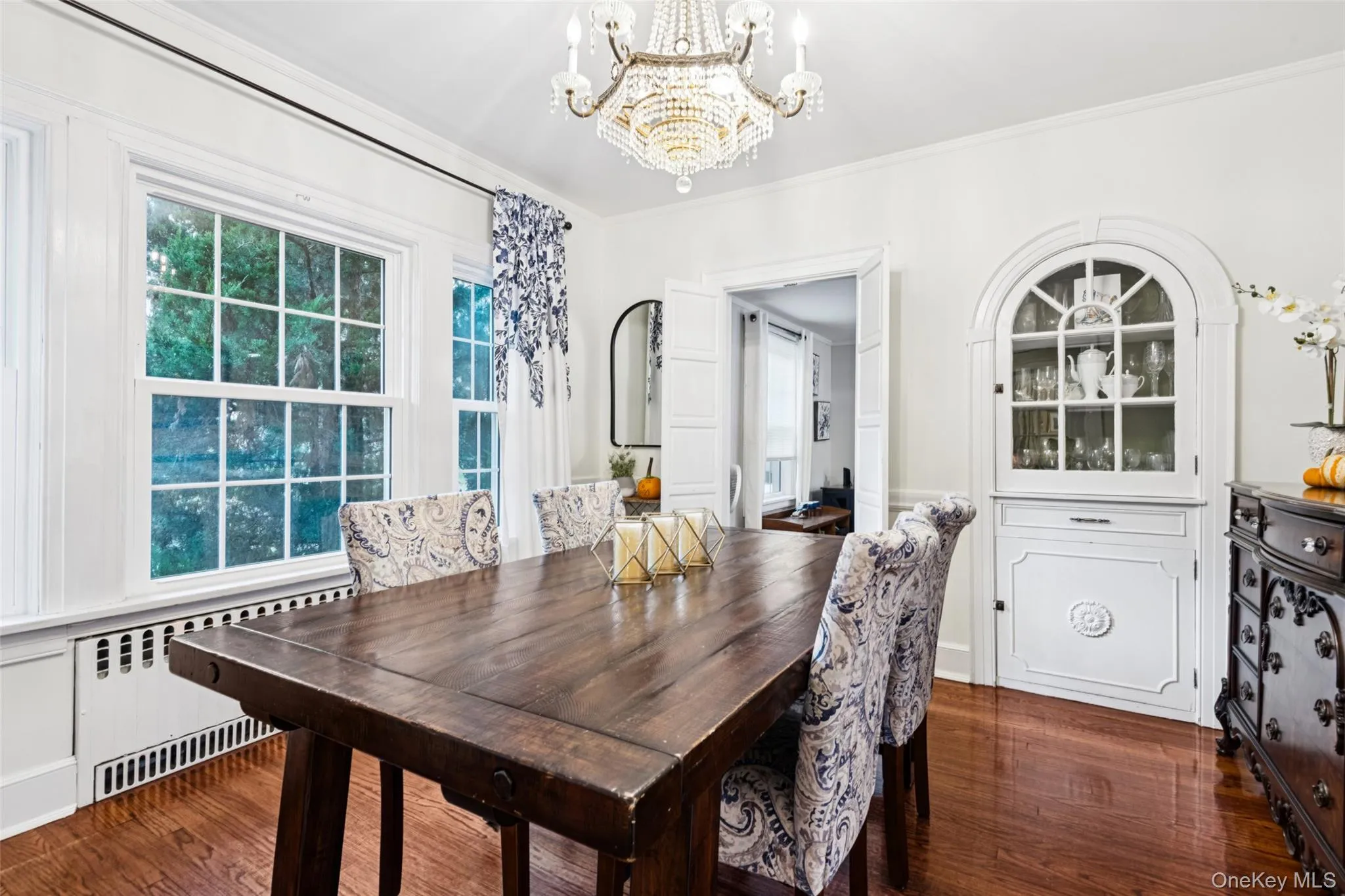 Dining area featuring radiator heating unit, crown molding, dark wood-style floors, and a chandelier Dining area featuring radiator heating unit, crown molding, dark wood-style floors, and a chandelier