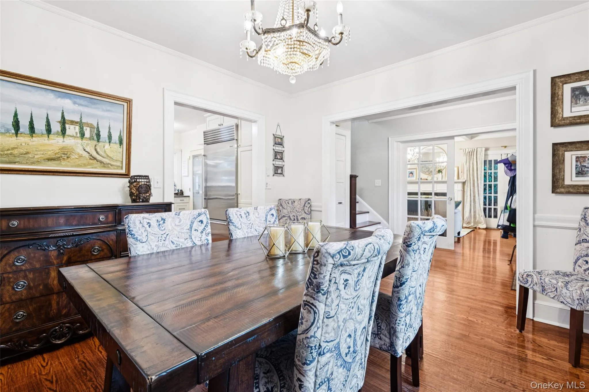 Dining area featuring ornamental molding, wood finished floors, a chandelier, and stairway Dining area featuring ornamental molding, wood finished floors, a chandelier, and stairway