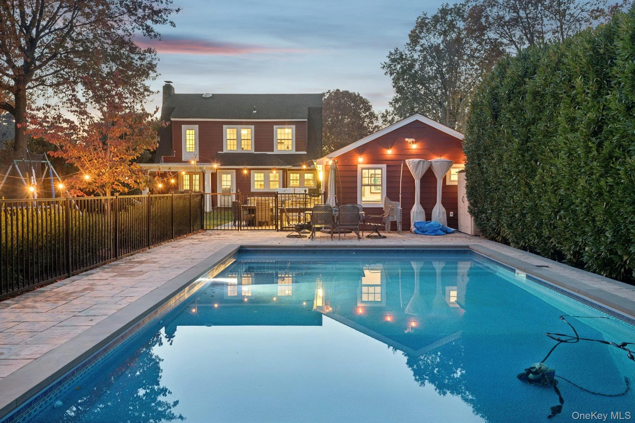 Pool at dusk featuring a patio and an outdoor structure Pool at dusk featuring a patio and an outdoor structure
