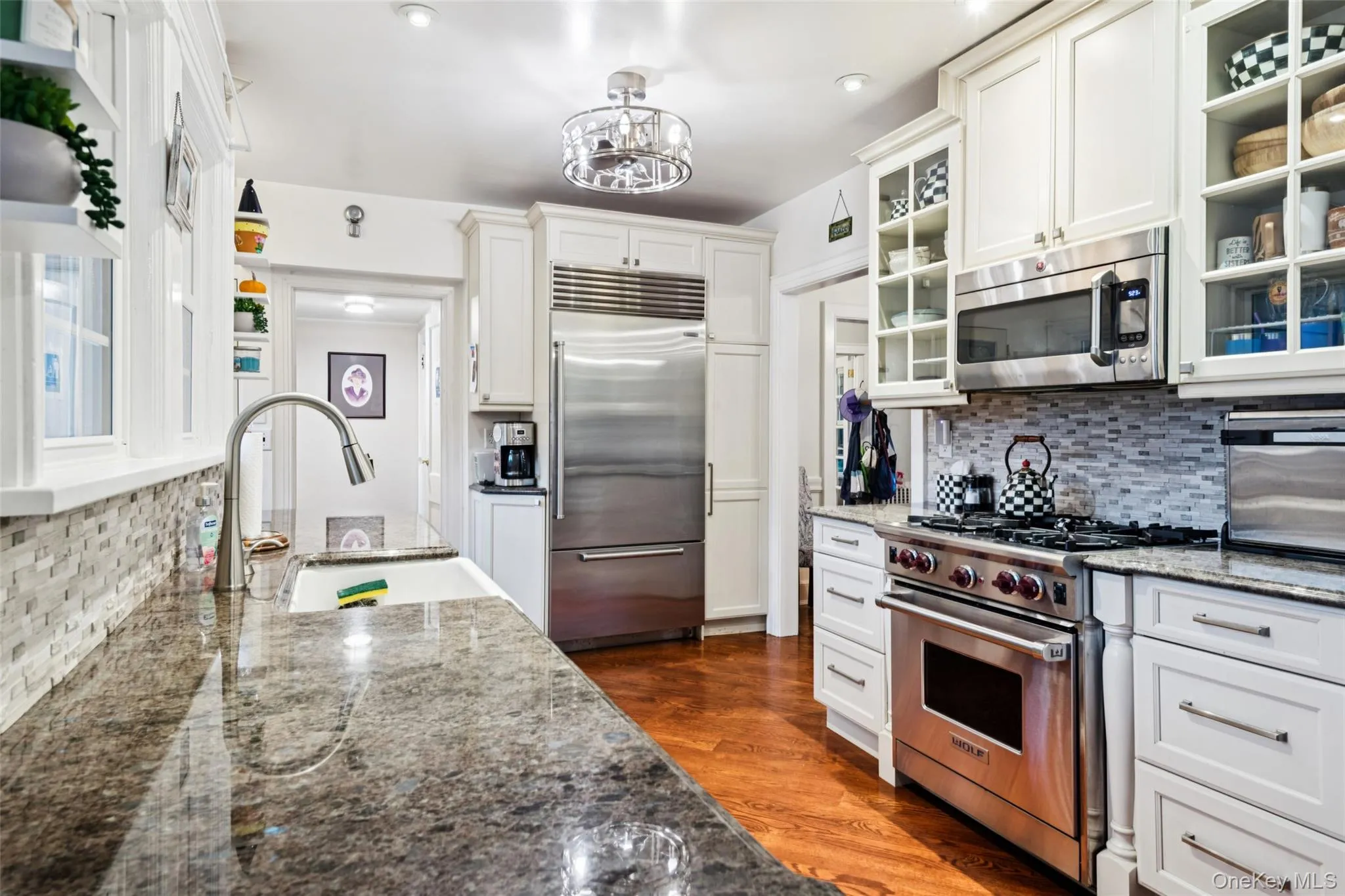 Kitchen featuring tasteful backsplash, dark stone countertops, high quality appliances, dark wood-type flooring, and recessed lighting Kitchen featuring tasteful backsplash, dark stone countertops, high quality appliances, dark wood-type flooring, and recessed lighting