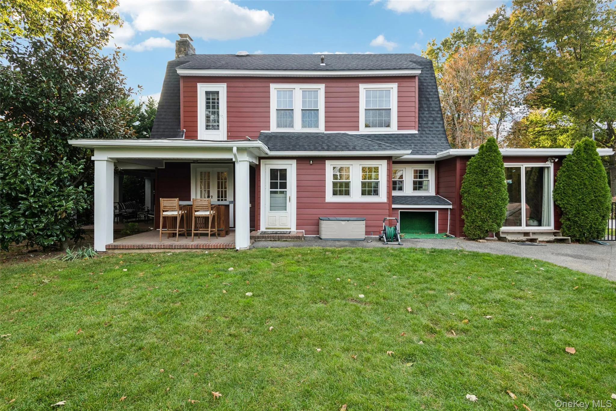 Back of property featuring a yard, a garage, asphalt driveway, roof with shingles, and a patio area Back of property featuring a yard, a garage, asphalt driveway, roof with shingles, and a patio area