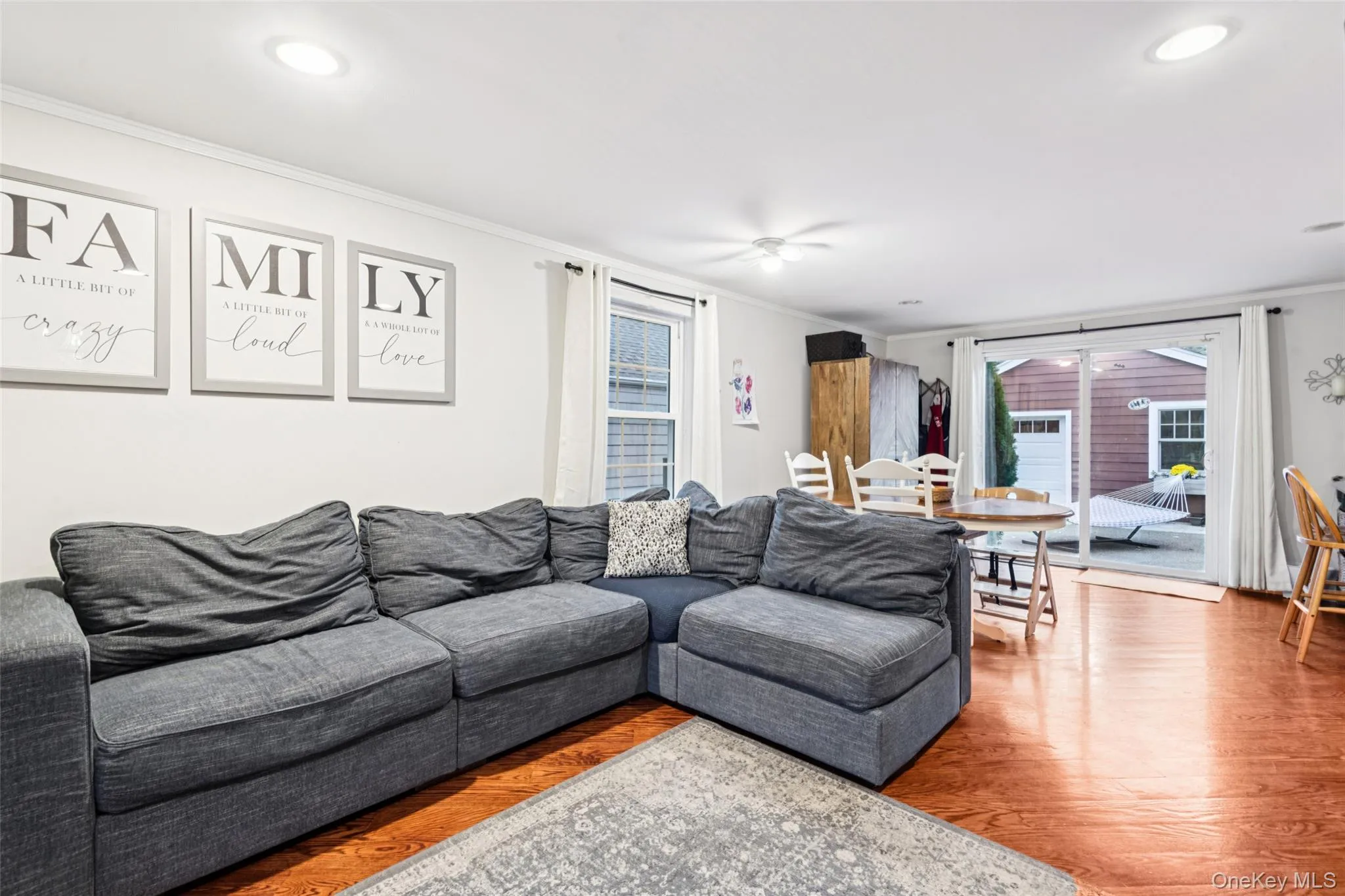Living area featuring crown molding, healthy amount of natural light, and wood finished floors Living area featuring crown molding, healthy amount of natural light, and wood finished floors