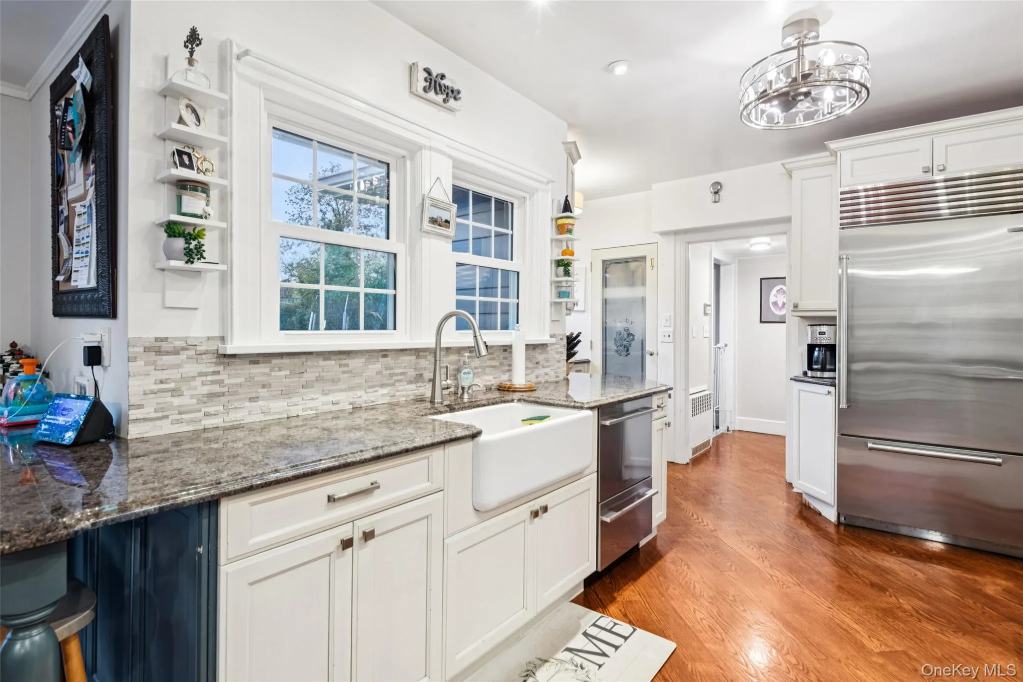 Kitchen featuring open shelves, white cabinets, dark stone countertops, tasteful backsplash, and stainless steel appliances Kitchen featuring open shelves, white cabinets, dark stone countertops, tasteful backsplash, and stainless steel appliances