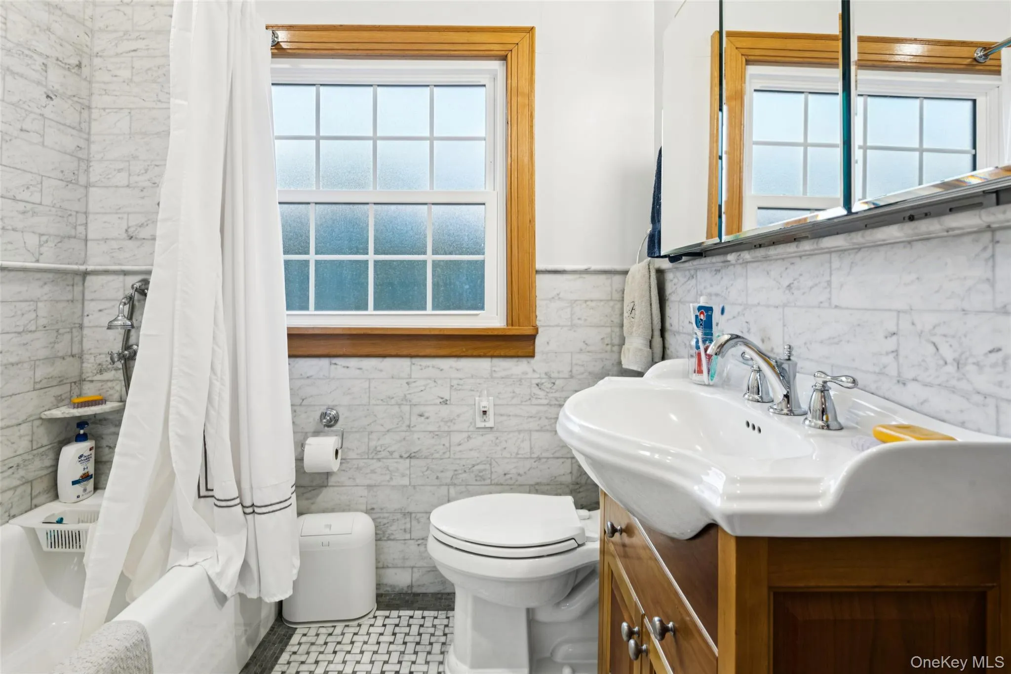 Full bathroom with tile walls, shower / bath combo with shower curtain, plenty of natural light, vanity, and wainscoting Full bathroom with tile walls, shower / bath combo with shower curtain, plenty of natural light, vanity, and wainscoting