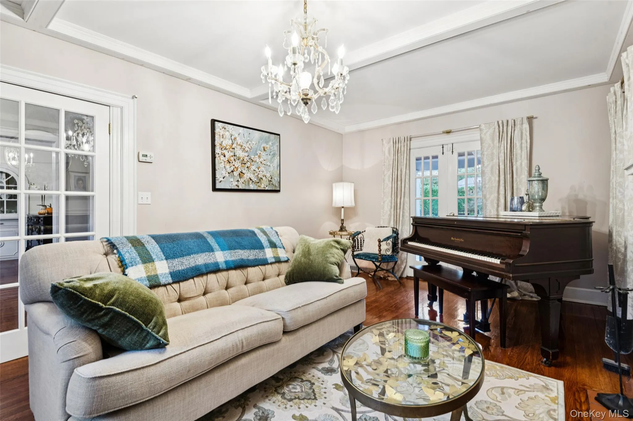 Living room with wood finished floors, crown molding, a chandelier, and beamed ceiling Living room with wood finished floors, crown molding, a chandelier, and beamed ceiling