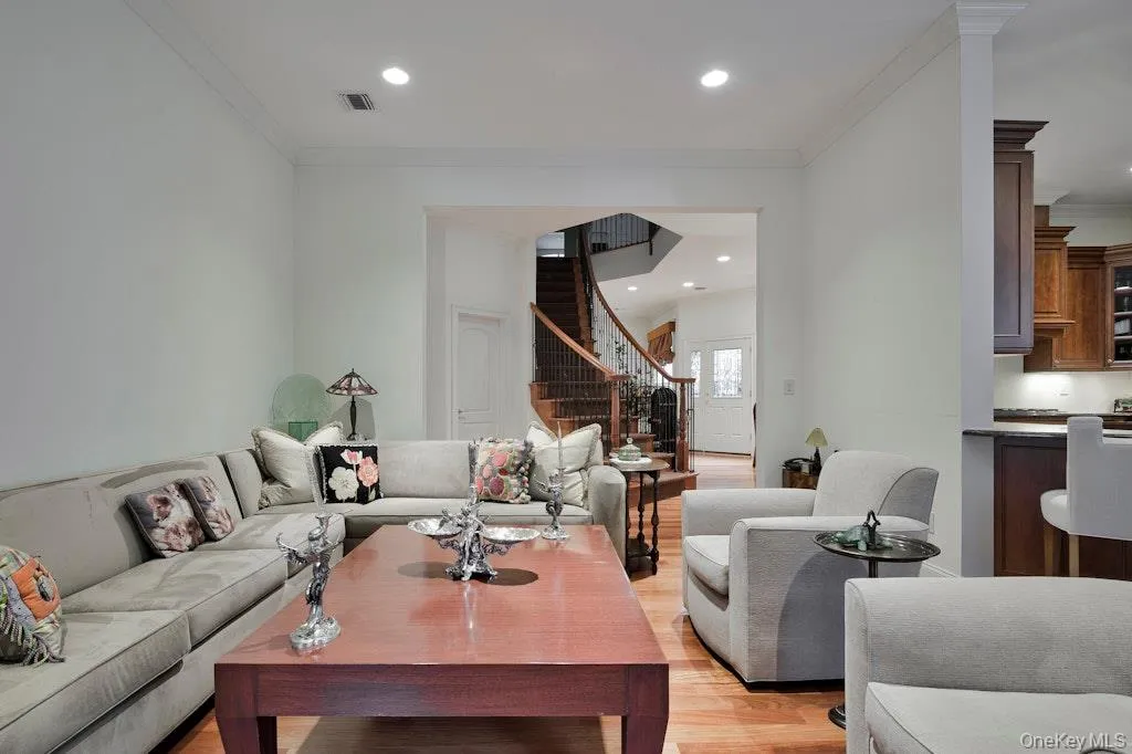 Living area featuring light wood-style floors, recessed lighting, stairway, and crown molding Living area featuring light wood-style floors, recessed lighting, stairway, and crown molding