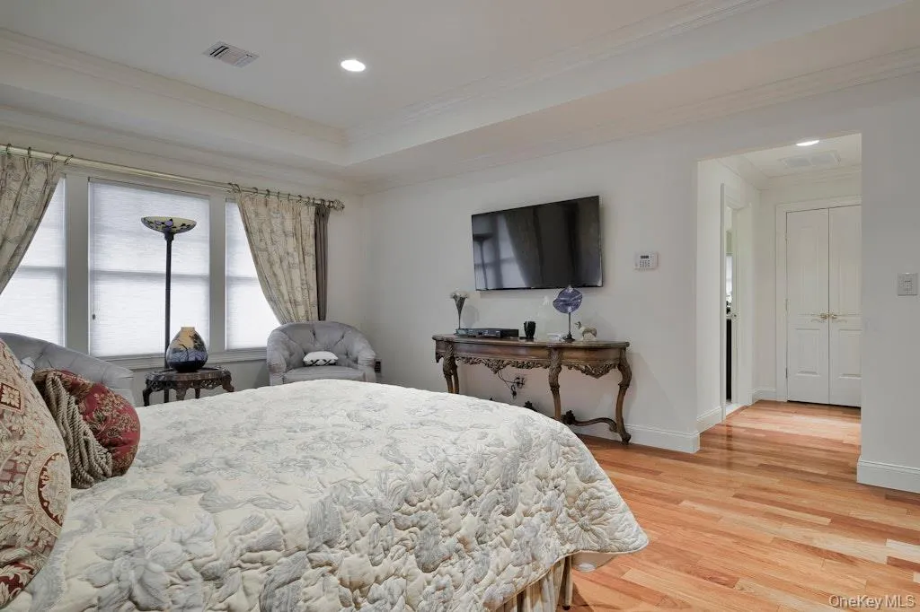 Bedroom featuring crown molding, light wood finished floors, recessed lighting, and a raised ceiling Bedroom featuring crown molding, light wood finished floors, recessed lighting, and a raised ceiling