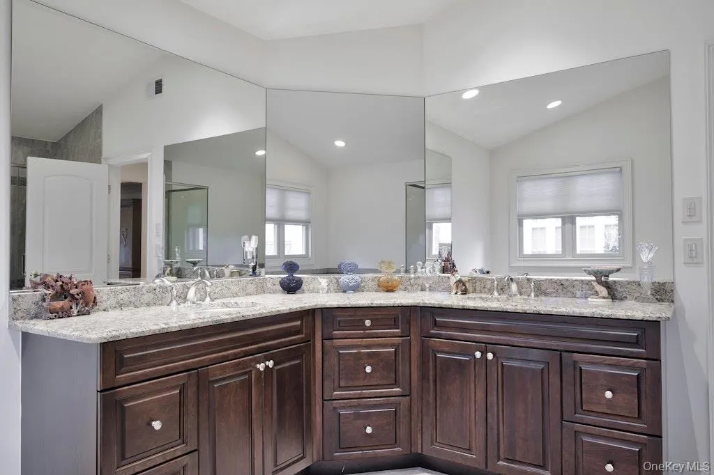 Bathroom with double vanity, vaulted ceiling, and recessed lighting Bathroom with double vanity, vaulted ceiling, and recessed lighting