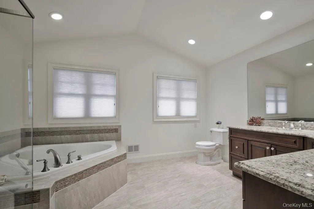 Bathroom with vanity, plenty of natural light, a garden tub, lofted ceiling, and recessed lighting Bathroom with vanity, plenty of natural light, a garden tub, lofted ceiling, and recessed lighting
