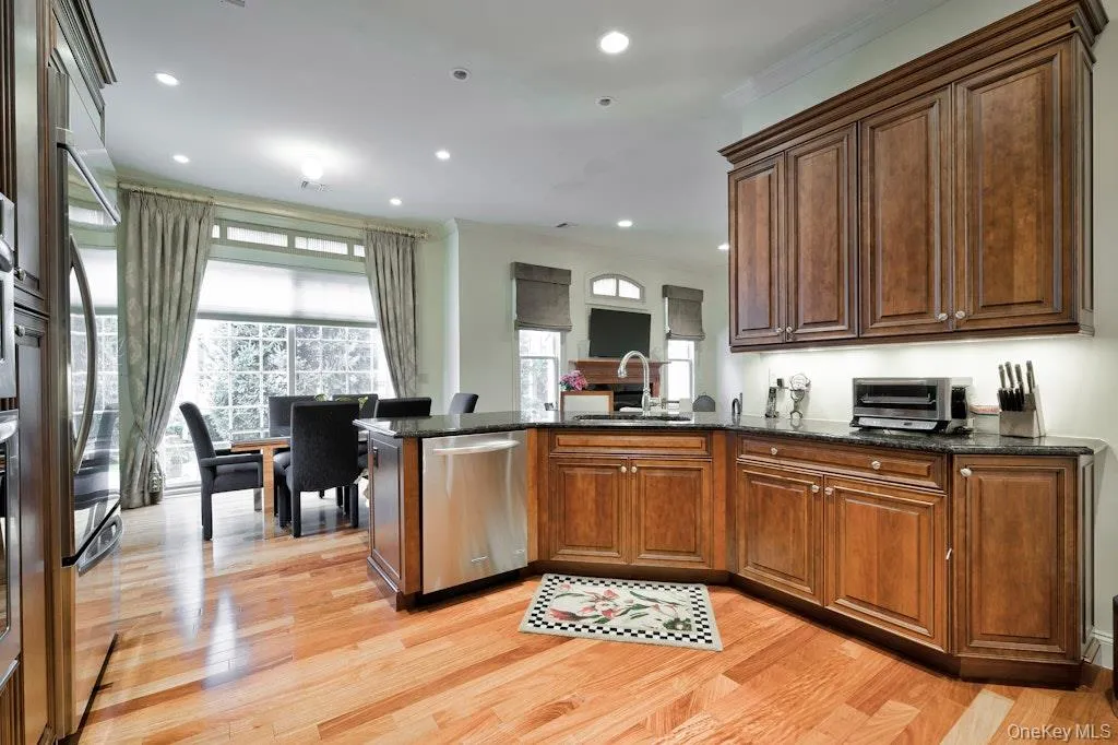 Kitchen with a peninsula, dark stone countertops, stainless steel appliances, light wood-style flooring, and ornamental molding Kitchen with a peninsula, dark stone countertops, stainless steel appliances, light wood-style flooring, and ornamental molding