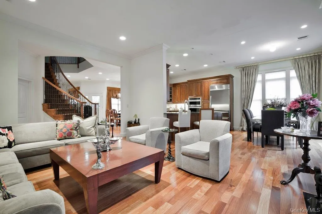 Living area with light wood-style floors, stairs, plenty of natural light, recessed lighting, and ornamental molding Living area with light wood-style floors, stairs, plenty of natural light, recessed lighting, and ornamental molding