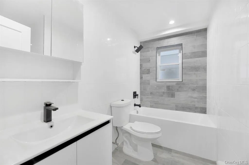 Bathroom with tile walls, vanity, bathtub / shower combination, and recessed lighting Bathroom with tile walls, vanity, bathtub / shower combination, and recessed lighting