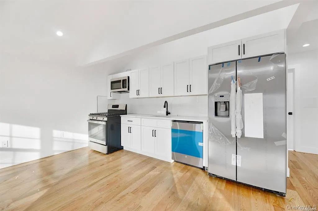 Kitchen featuring recessed lighting, stainless steel appliances, backsplash, white cabinets, and light wood-style flooring Kitchen featuring recessed lighting, stainless steel appliances, backsplash, white cabinets, and light wood-style flooring
