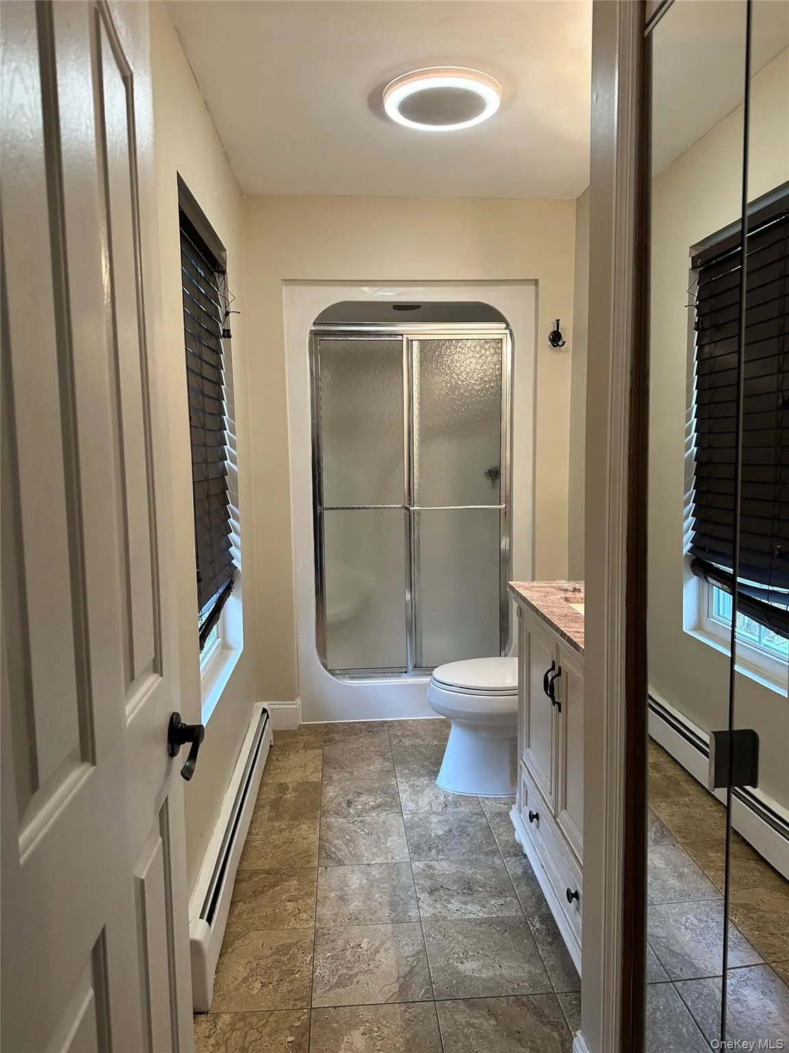 Full bathroom with vanity, a baseboard radiator, and a stall shower Full bathroom with vanity, a baseboard radiator, and a stall shower