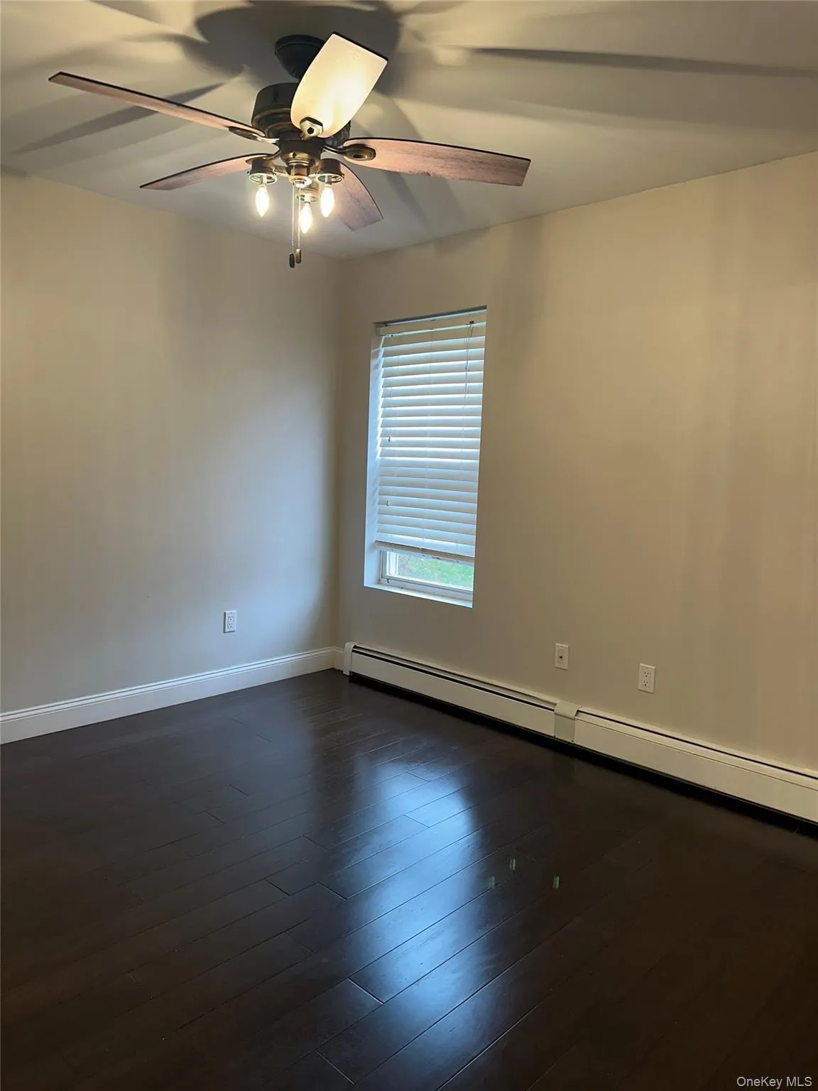 bedroom featuring a baseboard heating unit, dark wood-type flooring, and a ceiling fan bedroom featuring a baseboard heating unit, dark wood-type flooring, and a ceiling fan