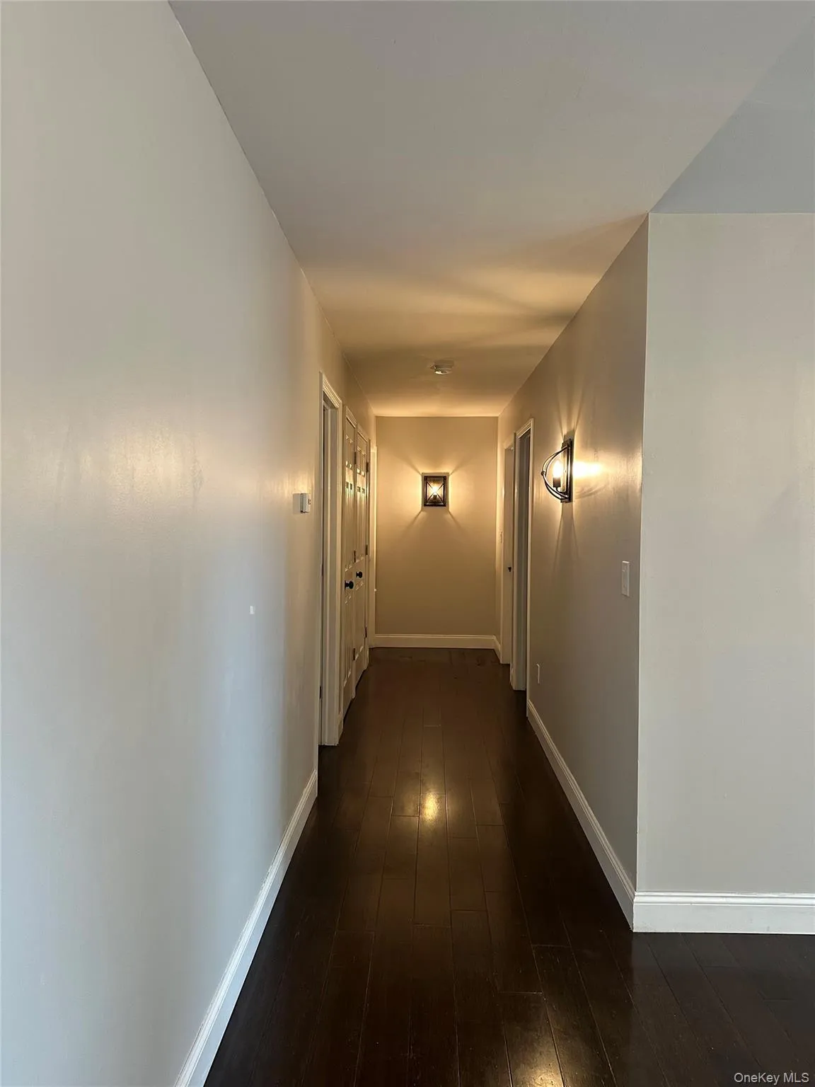 Corridor featuring dark wood-style floors and baseboards Corridor featuring dark wood-style floors and baseboards