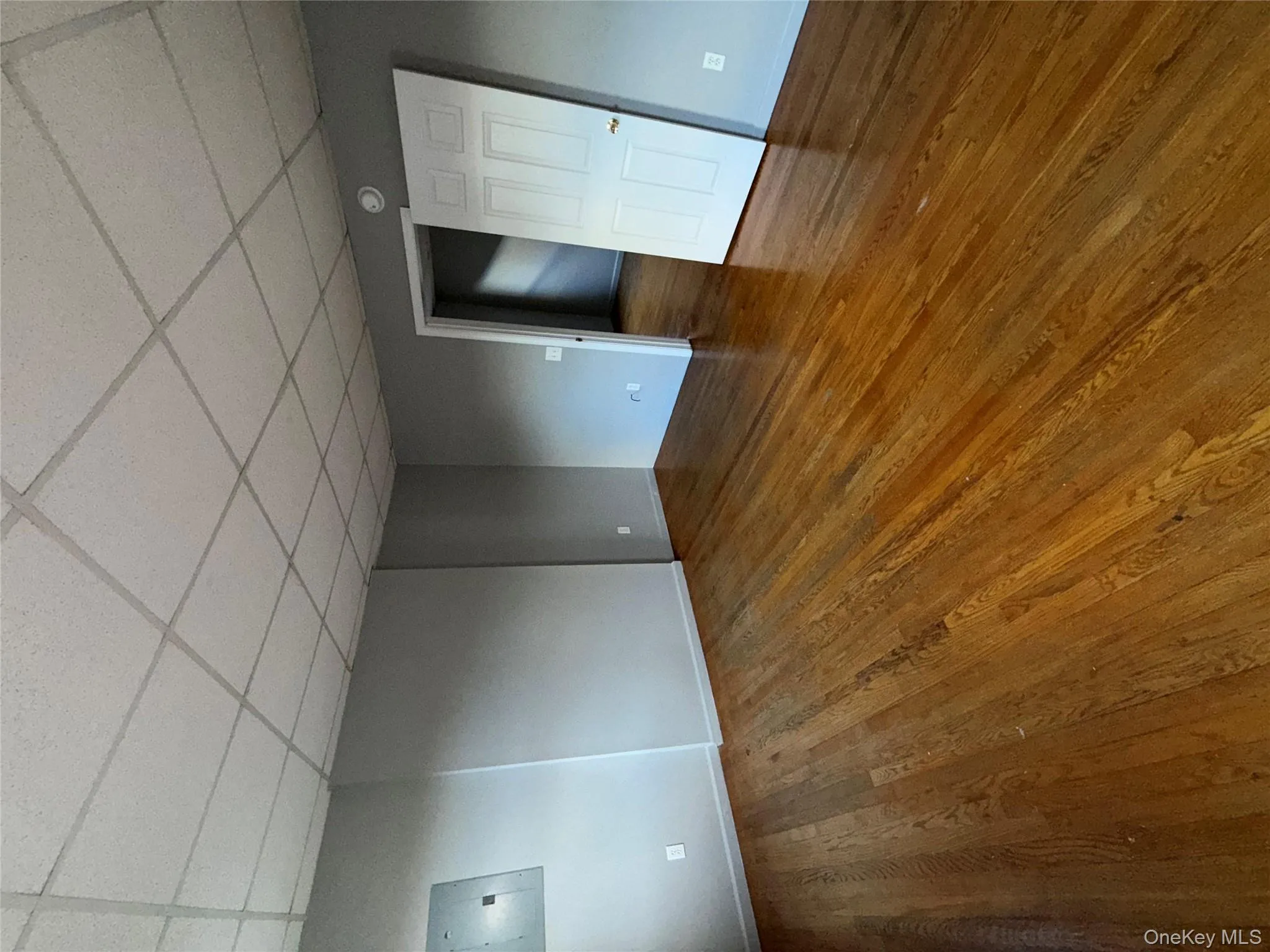 Spare room with electric panel, dark wood-type flooring, and a paneled ceiling Spare room with electric panel, dark wood-type flooring, and a paneled ceiling