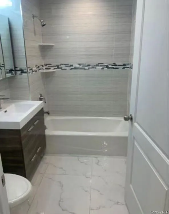 Full bathroom featuring vanity, shower / washtub combination, and light marble finish flooring Full bathroom featuring vanity, shower / washtub combination, and light marble finish flooring