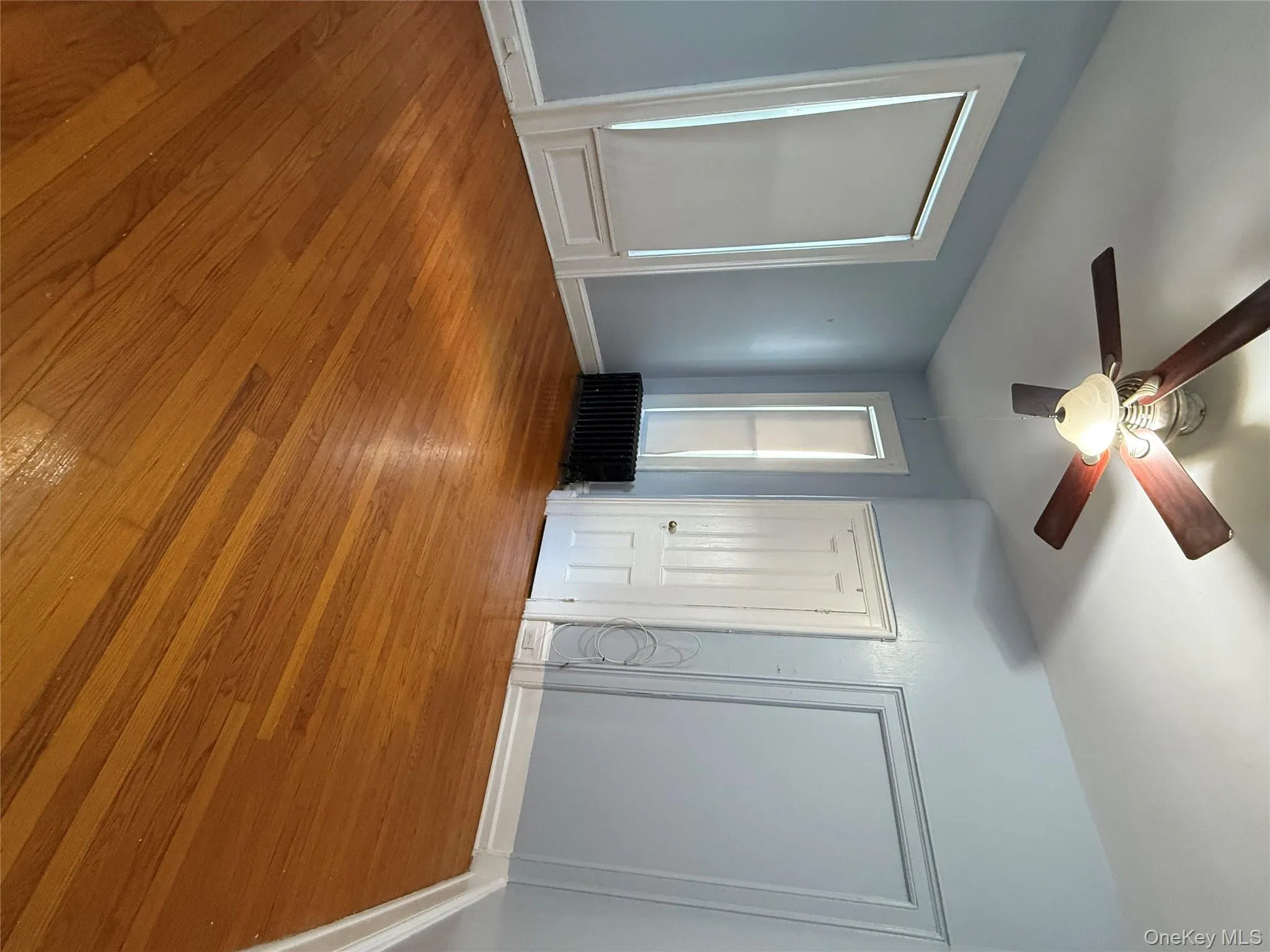 Unfurnished bedroom featuring light wood finished floors, multiple closets, radiator, and ceiling fan Unfurnished bedroom featuring light wood finished floors, multiple closets, radiator, and ceiling fan