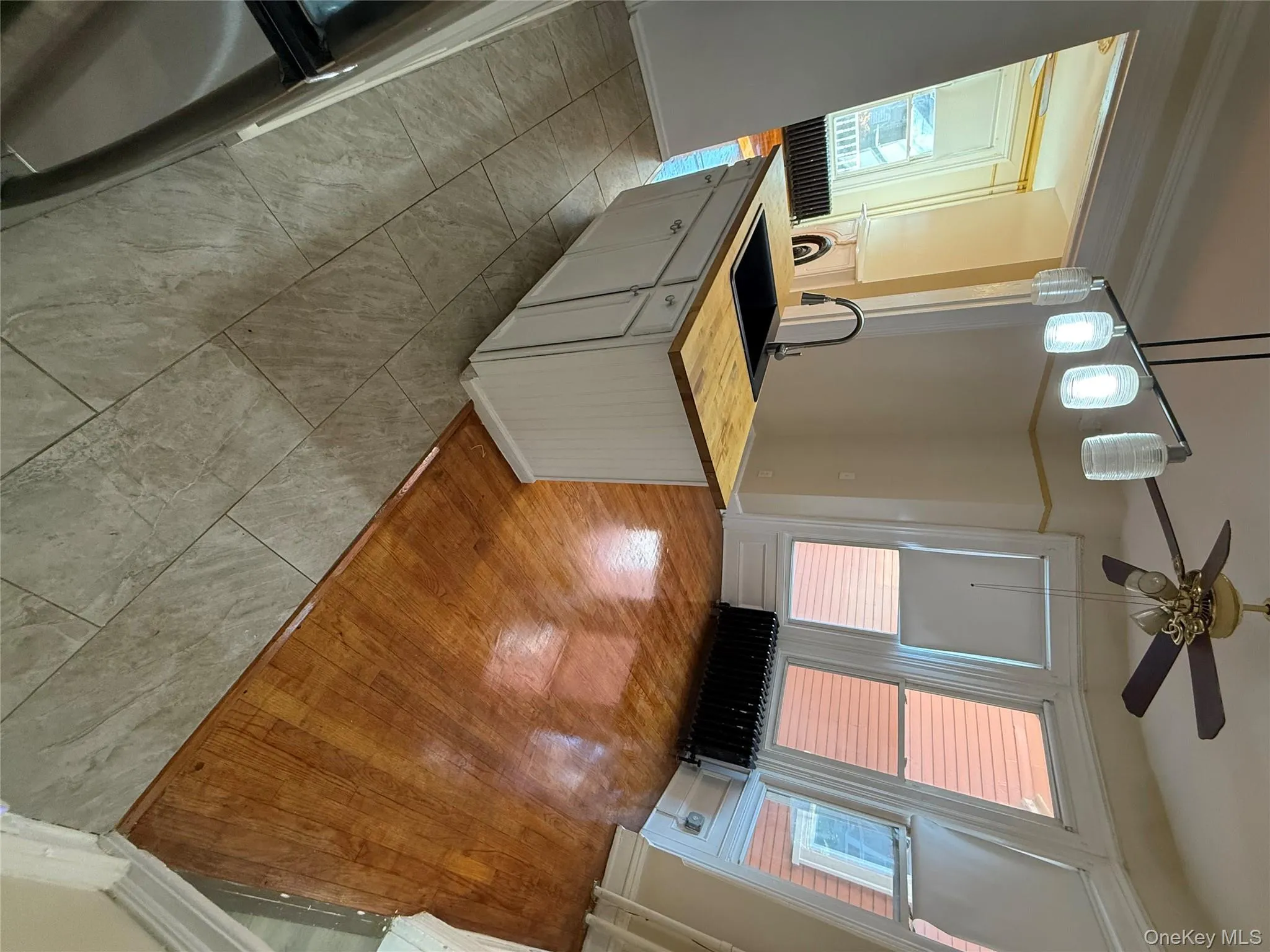 Kitchen with wooden counters, white cabinetry, decorative light fixtures, light tile patterned floors, and radiator Kitchen with wooden counters, white cabinetry, decorative light fixtures, light tile patterned floors, and radiator