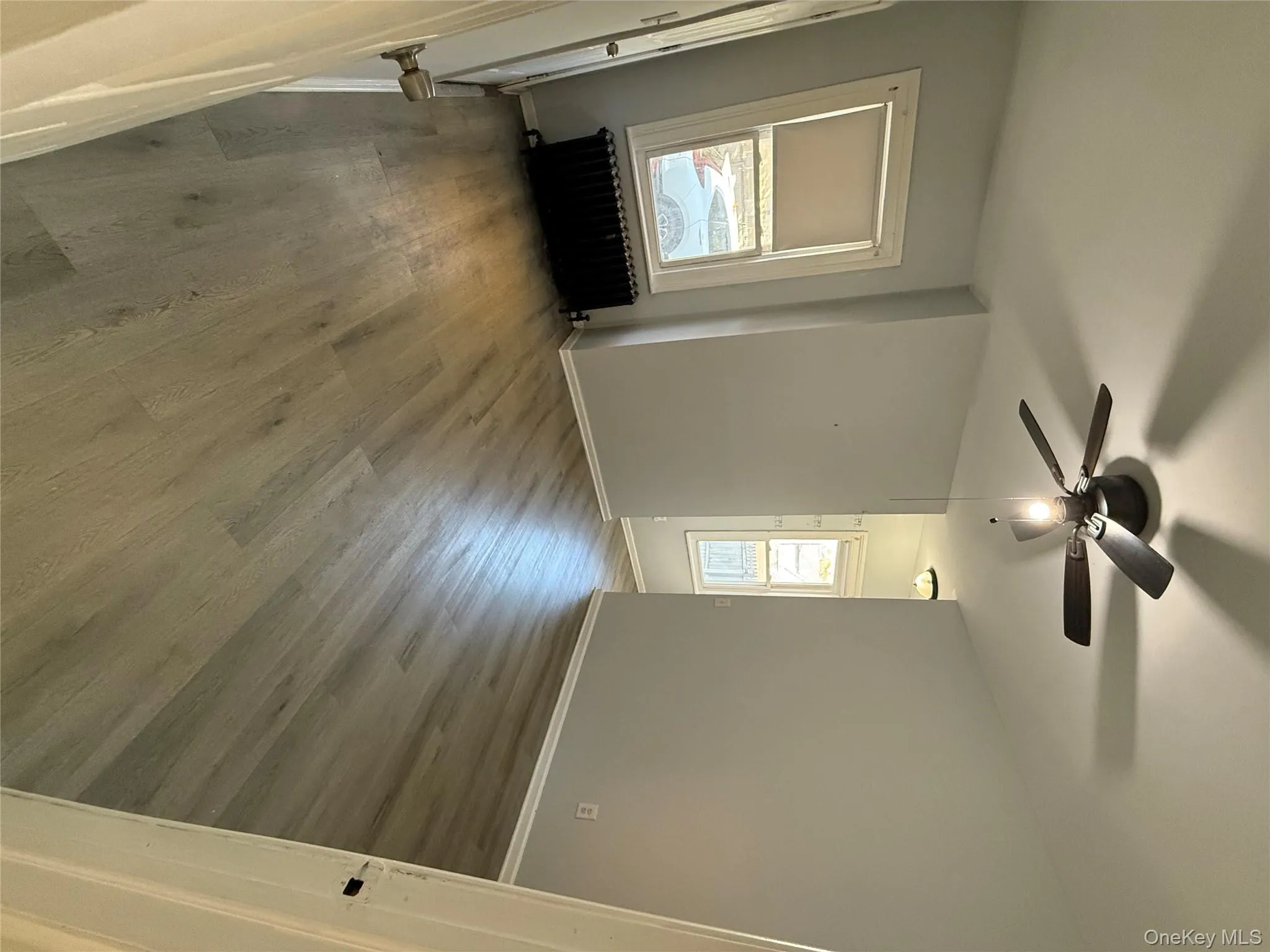 Unfurnished room with wood finished floors, radiator heating unit, and ceiling fan Unfurnished room with wood finished floors, radiator heating unit, and ceiling fan